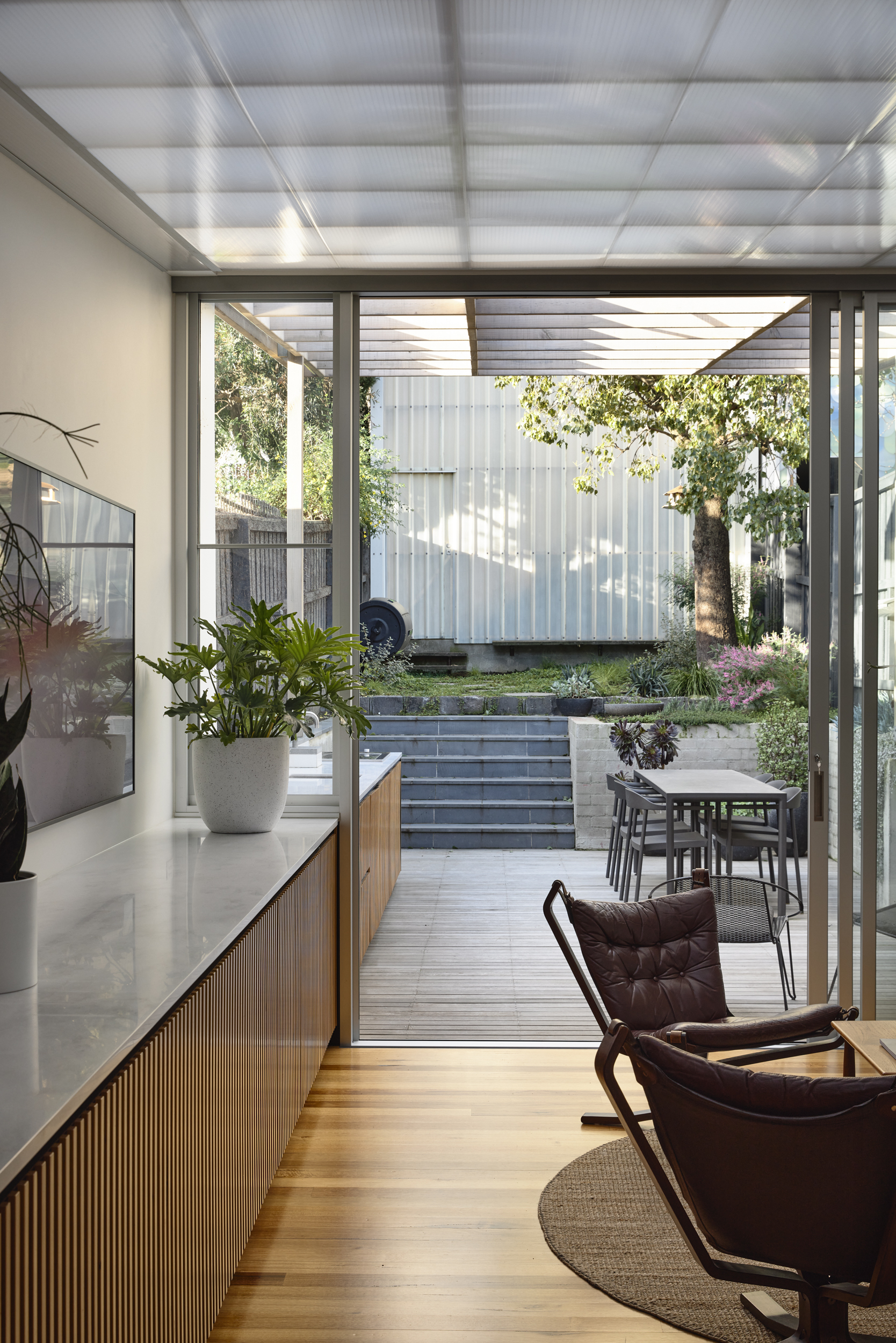 Living area opening through sliding glass doors to courtyard with stepped concrete planters and tree