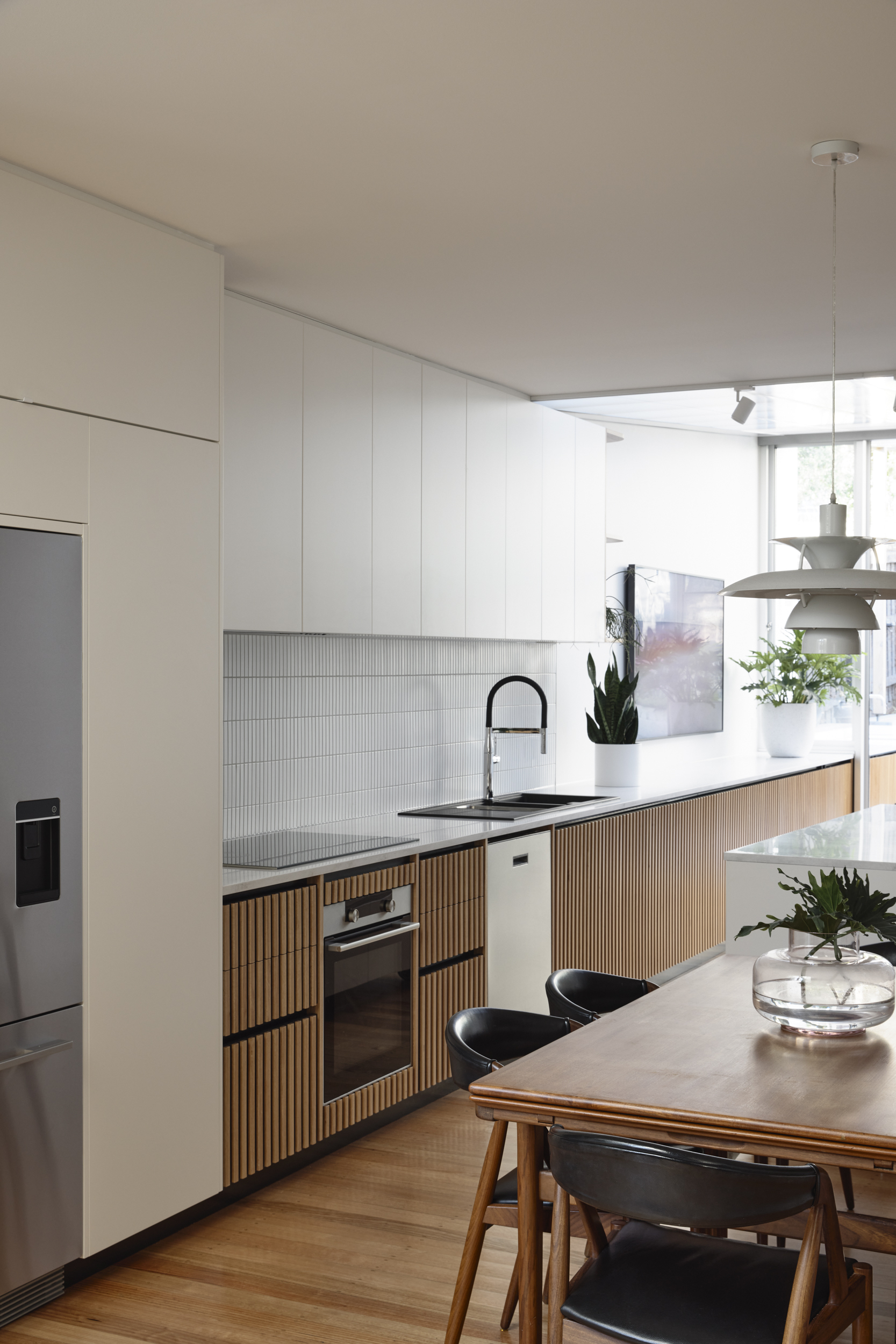 Kitchen with white upper cabinets and timber-slat base units beneath a white ceiling grid