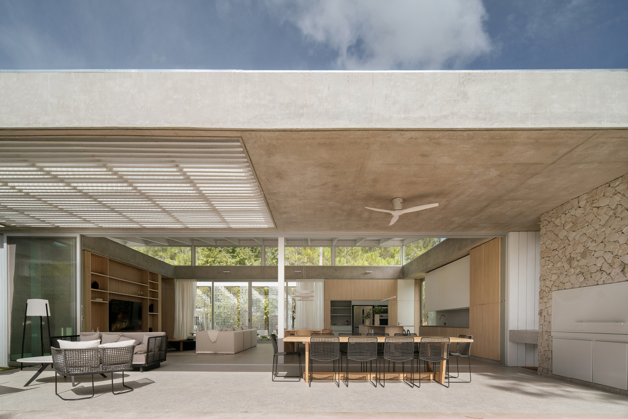 Covered terrace with timber ceiling, stone accent wall and dining area overlooking trees