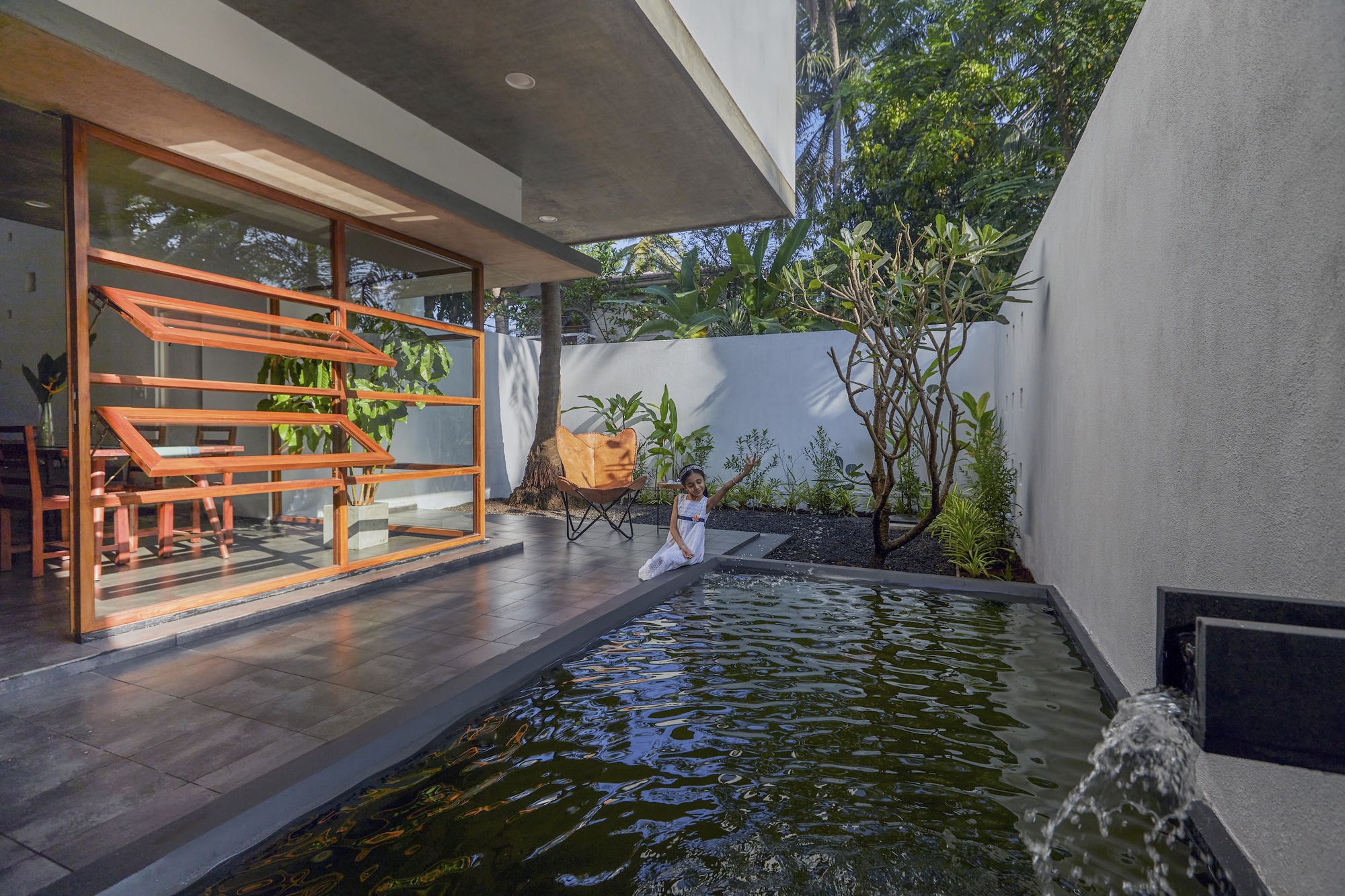 Courtyard water feature with timber deck and horizontal louvered screen beside planted greenery