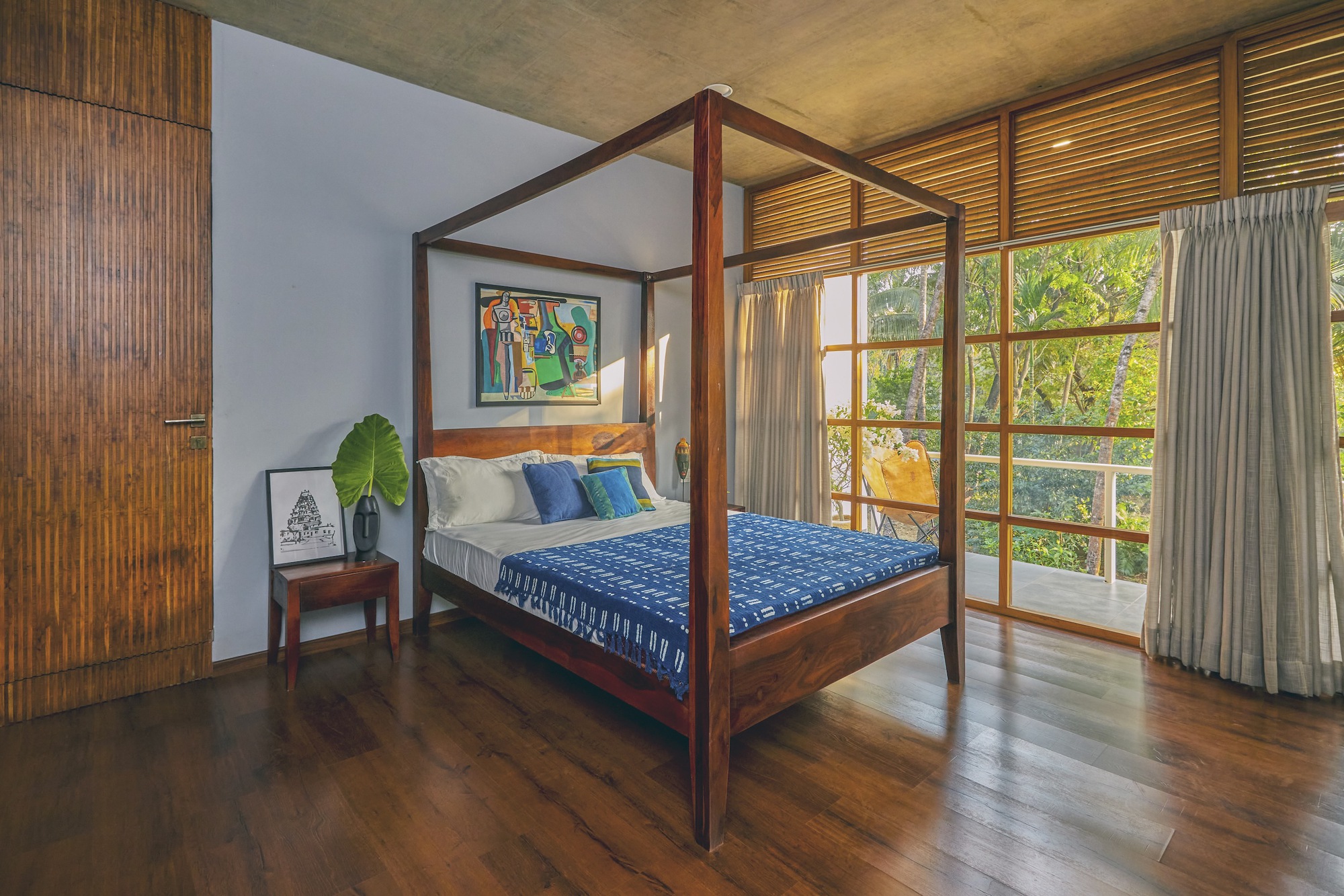 Bedroom with four-poster timber bed and grid-paned sliding doors opening to a private balcony
