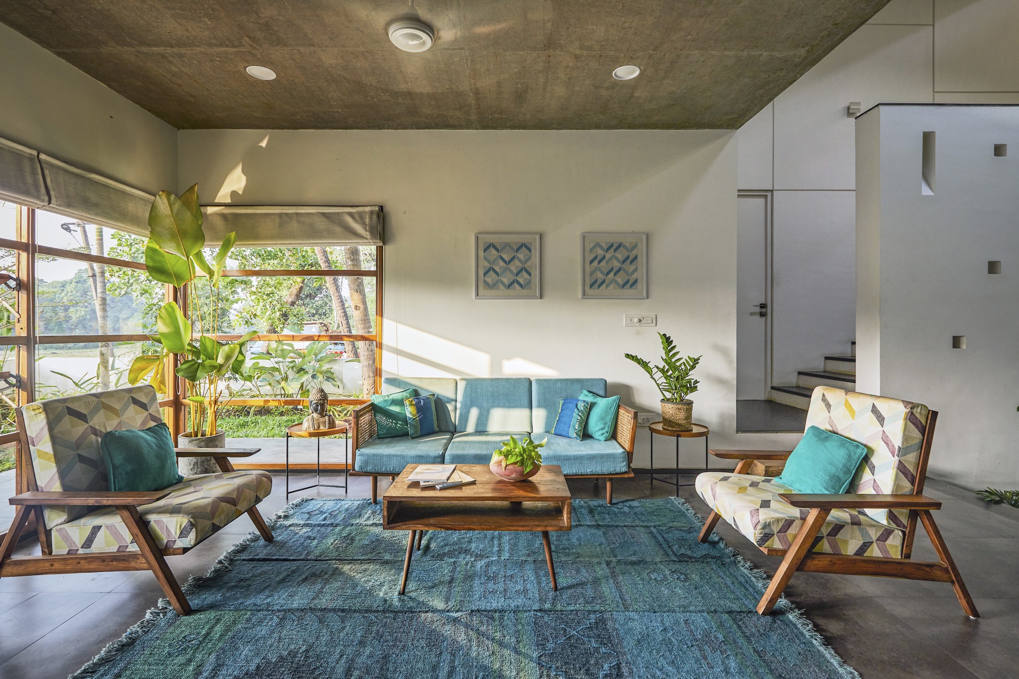 Living room with exposed concrete ceiling and gridded windows overlooking greenery in morning light