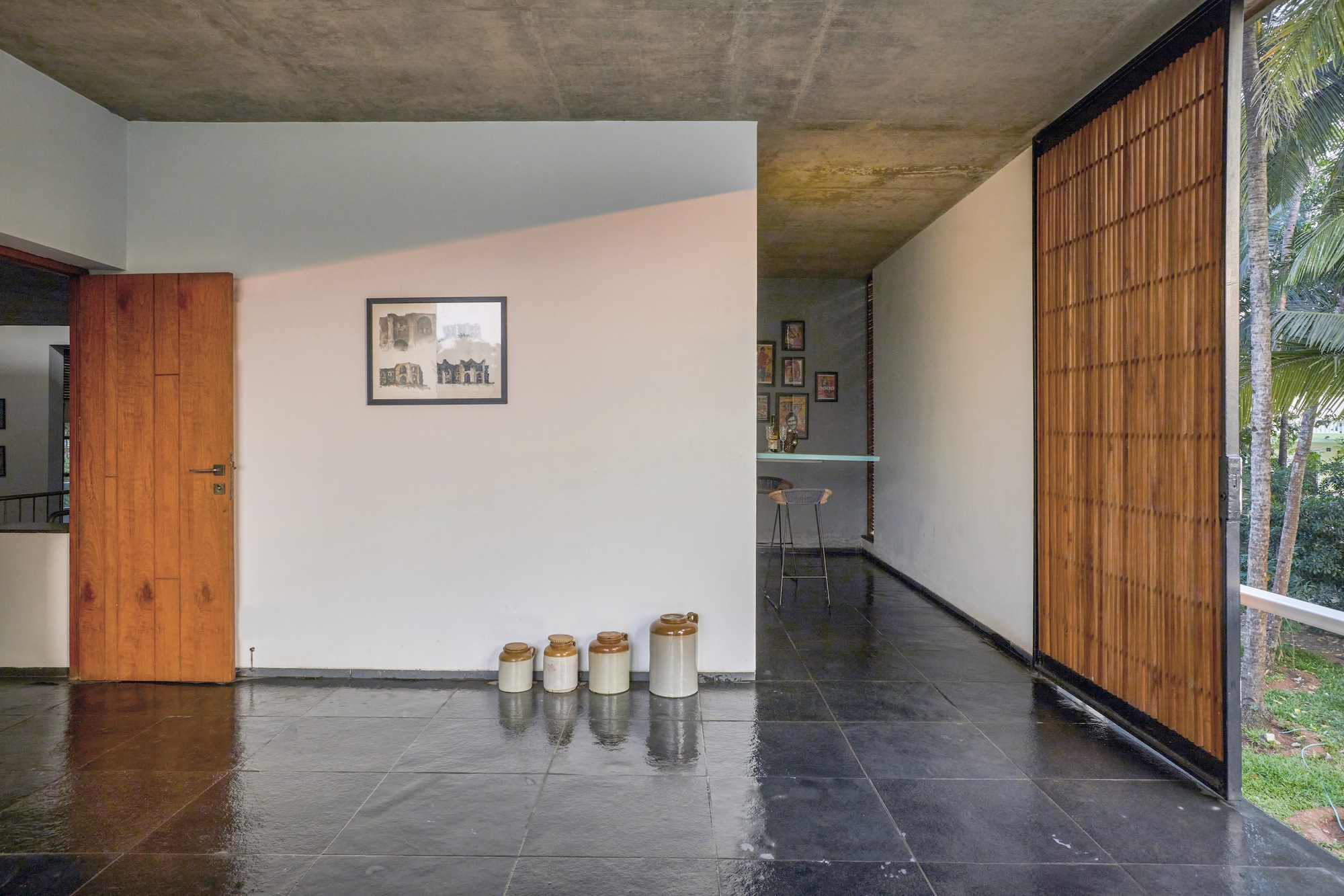 Hallway with black stone floor and sliding bamboo screen beside a timber door and concrete soffit
