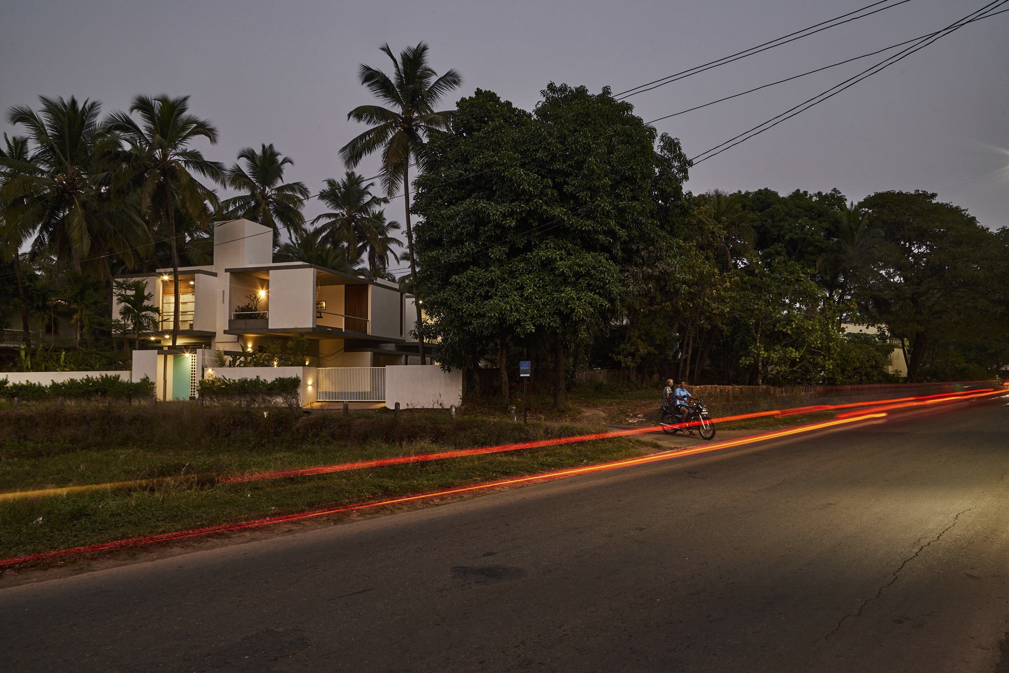 Long exposure view from the road at twilight capturing vehicle light trails and palms