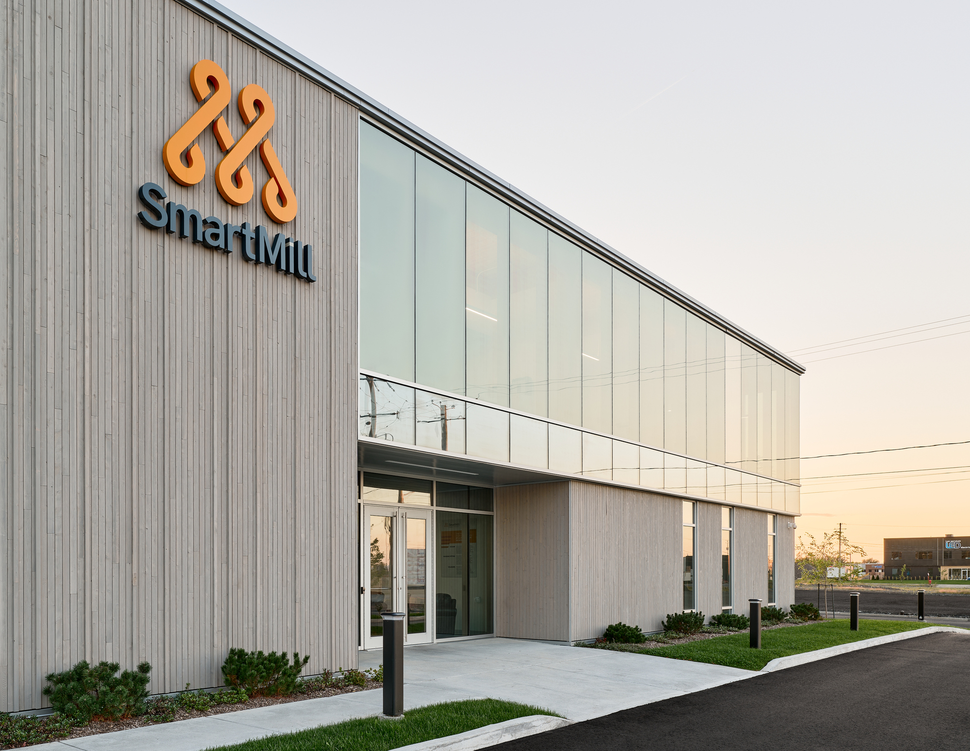 Entrance facade with vertical metal cladding and translucent panel upper story photographed at sunset
