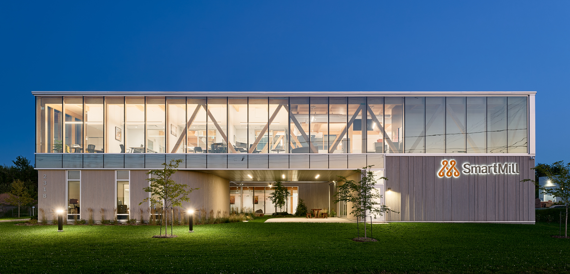 Two-story facade with diagonal timber bracing and corrugated metal cladding under a deep blue evening sky