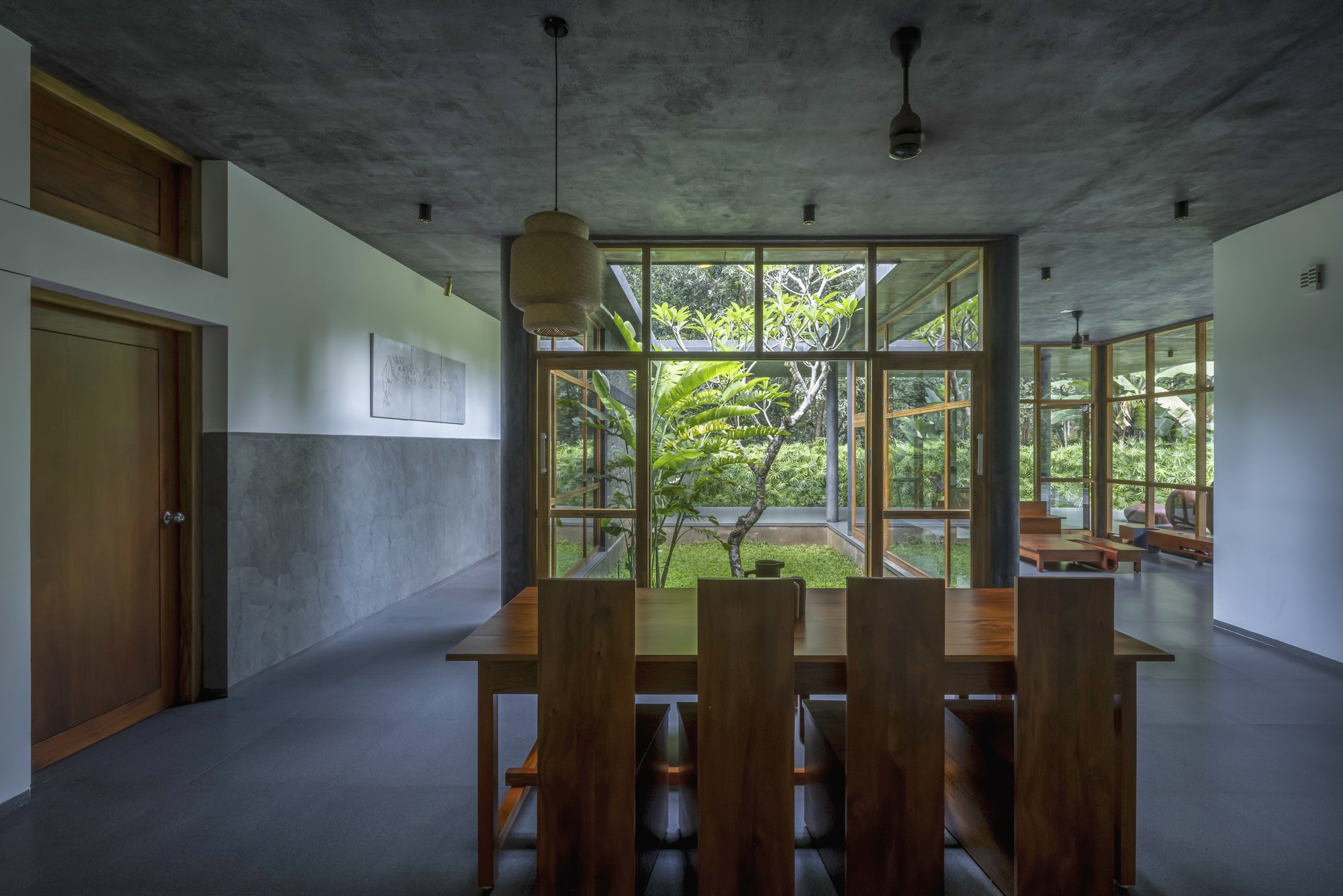 Dining area with timber table and chairs beneath board-formed concrete ceiling and pendant light fixtures