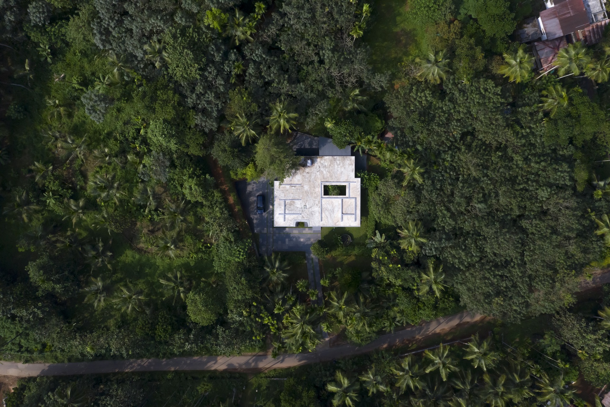 Aerial view of the compound's white roofs nestled within dense coconut palm canopy