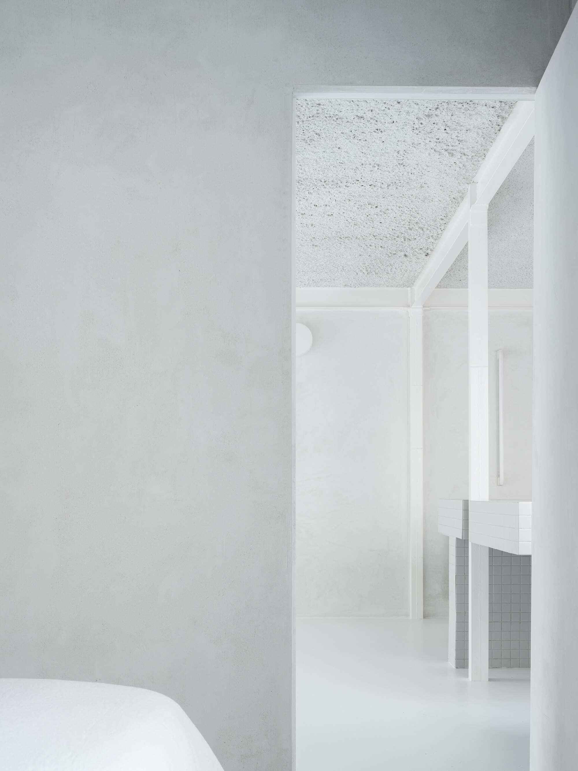 White painted steel frame partition beneath terrazzo ceiling with view through to kitchen beyond