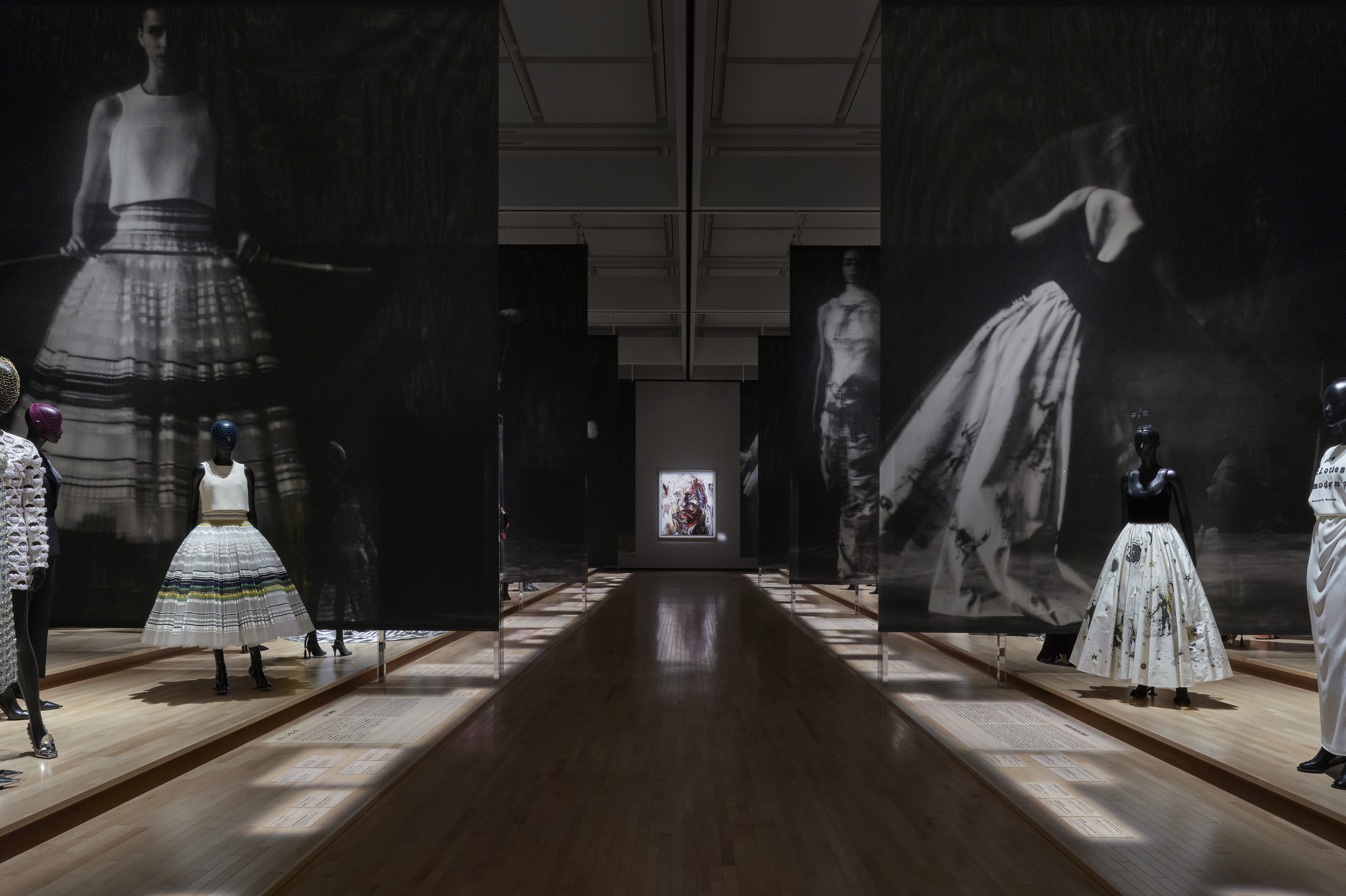 Gallery hall with timber flooring and large-scale black and white photographic projections flanking display cases