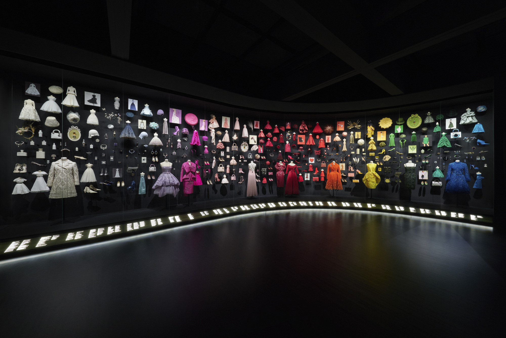 Panoramic display wall showing garments and objects arranged by color gradient from white to blue