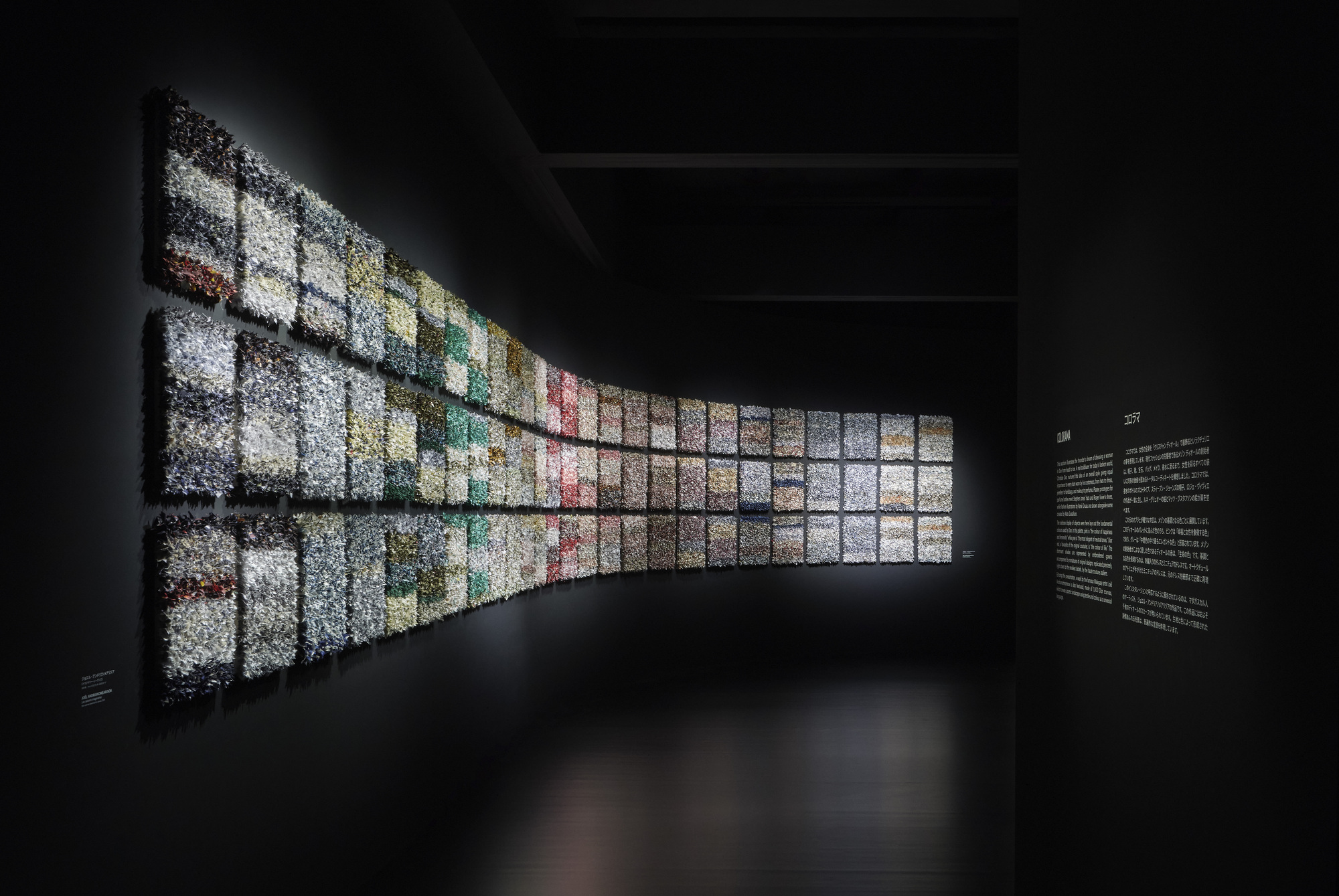 Curved backlit wall composed of gridded image panels transitioning through the color spectrum