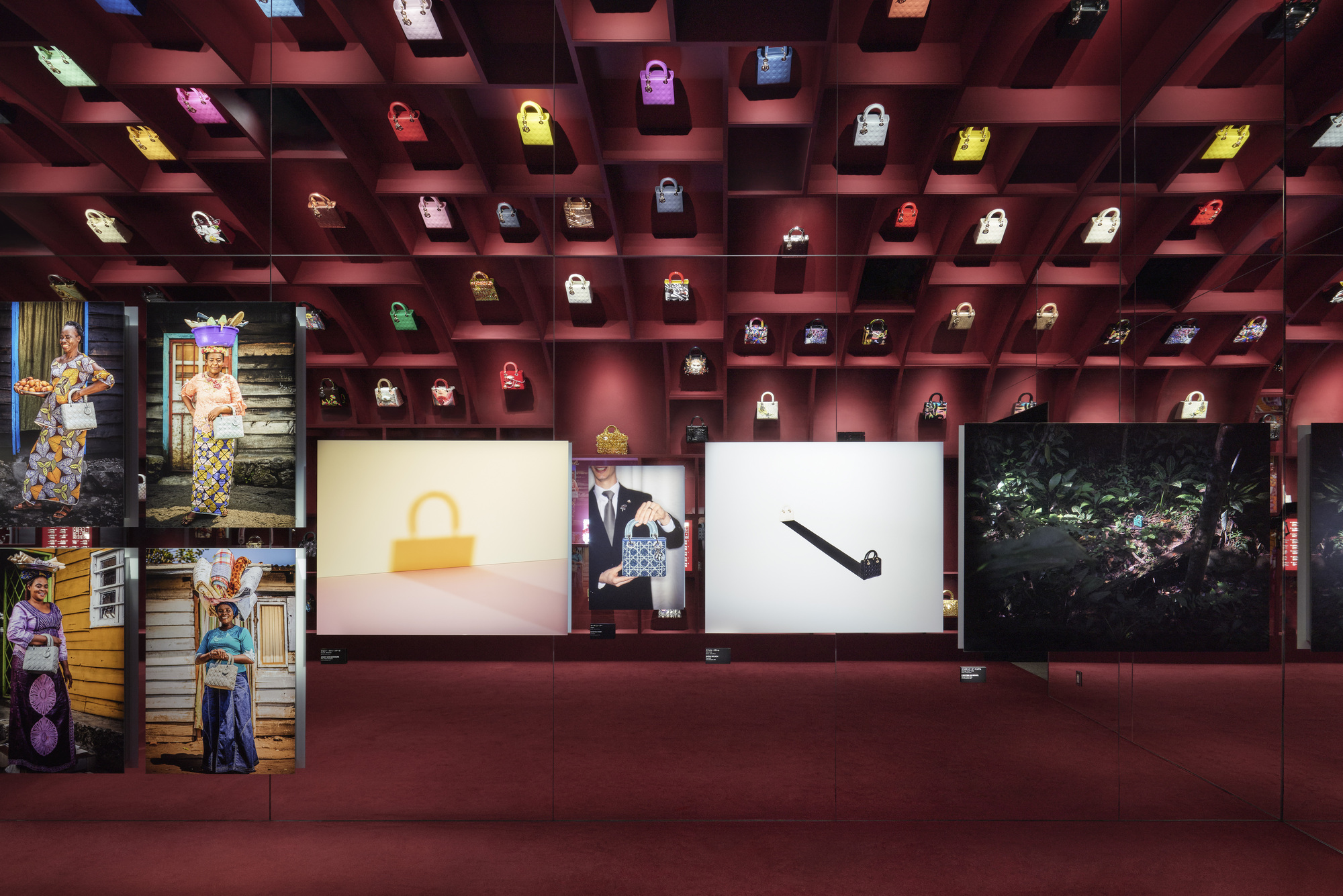 Coffered ceiling grid displaying illuminated handbags above burgundy walls and backlit panels