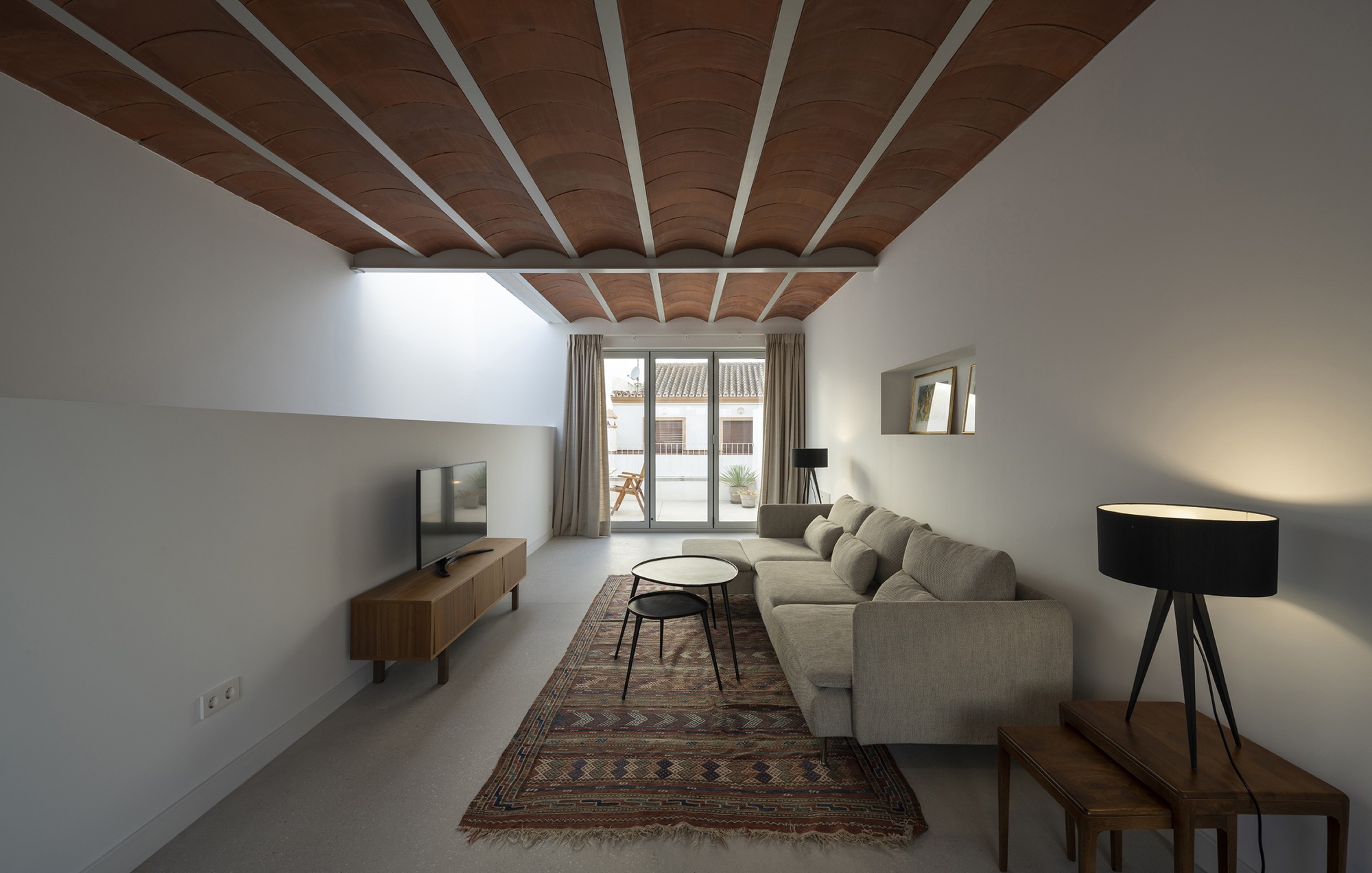 Living room with timber-clad ceiling beams and clerestory window bringing natural light above the sofa