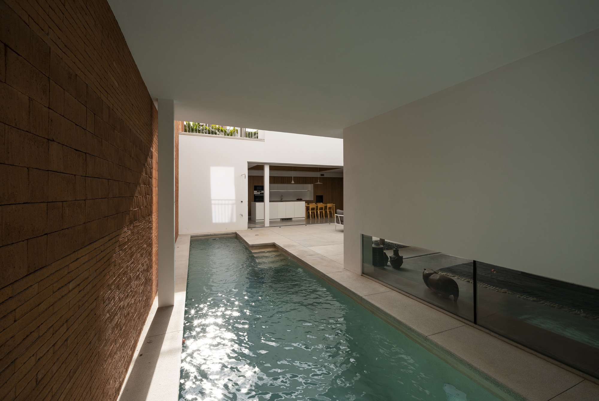 Indoor lap pool with timber cladding on one wall and water reflecting sunlight from above