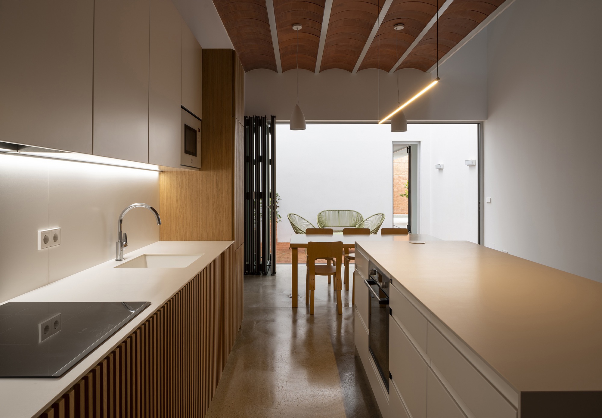 Kitchen island with integrated sink and ribbed timber cabinetry beneath a vaulted wood ceiling