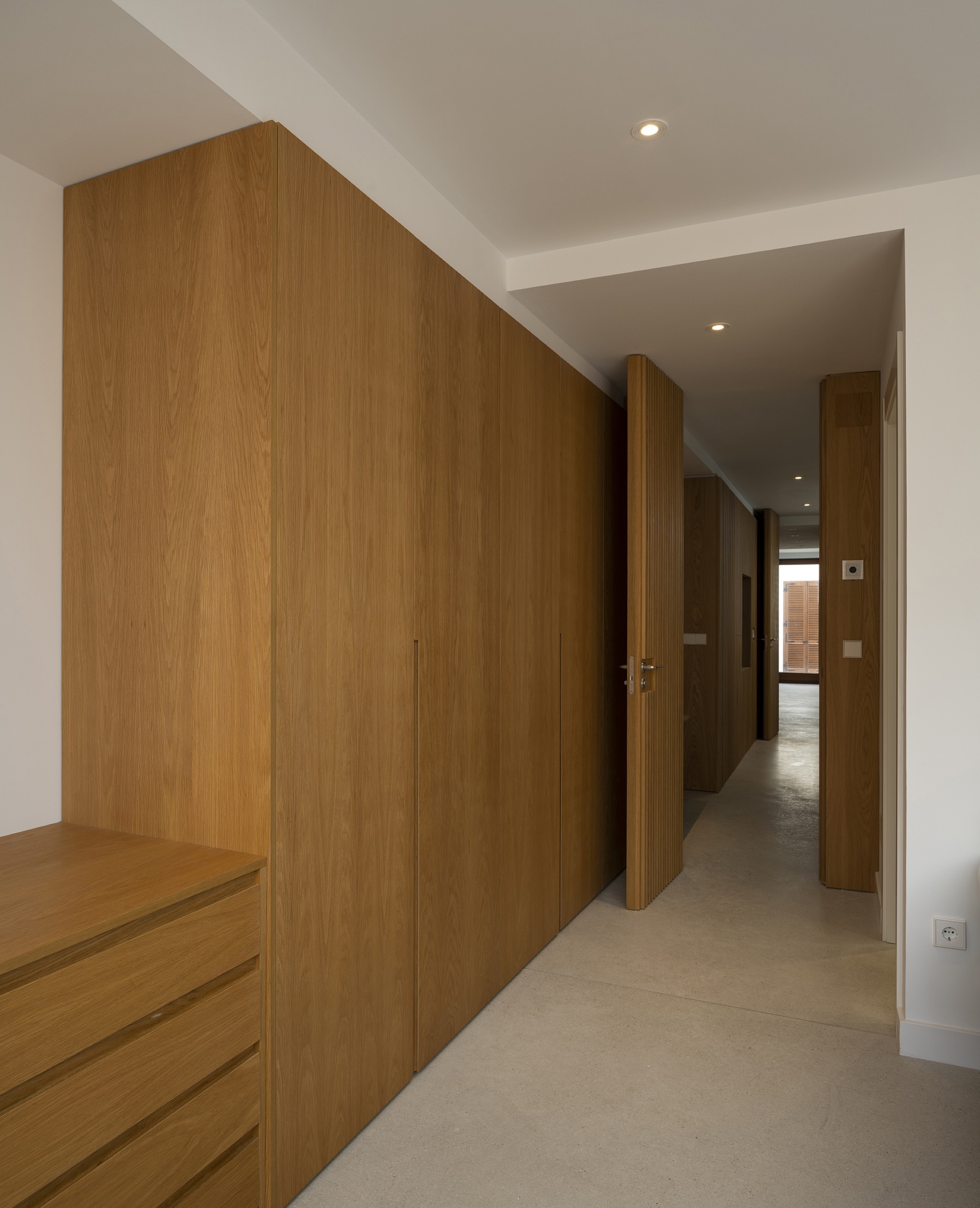 Corridor with built-in oak veneer wardrobes and ceiling recess forming a linear passage