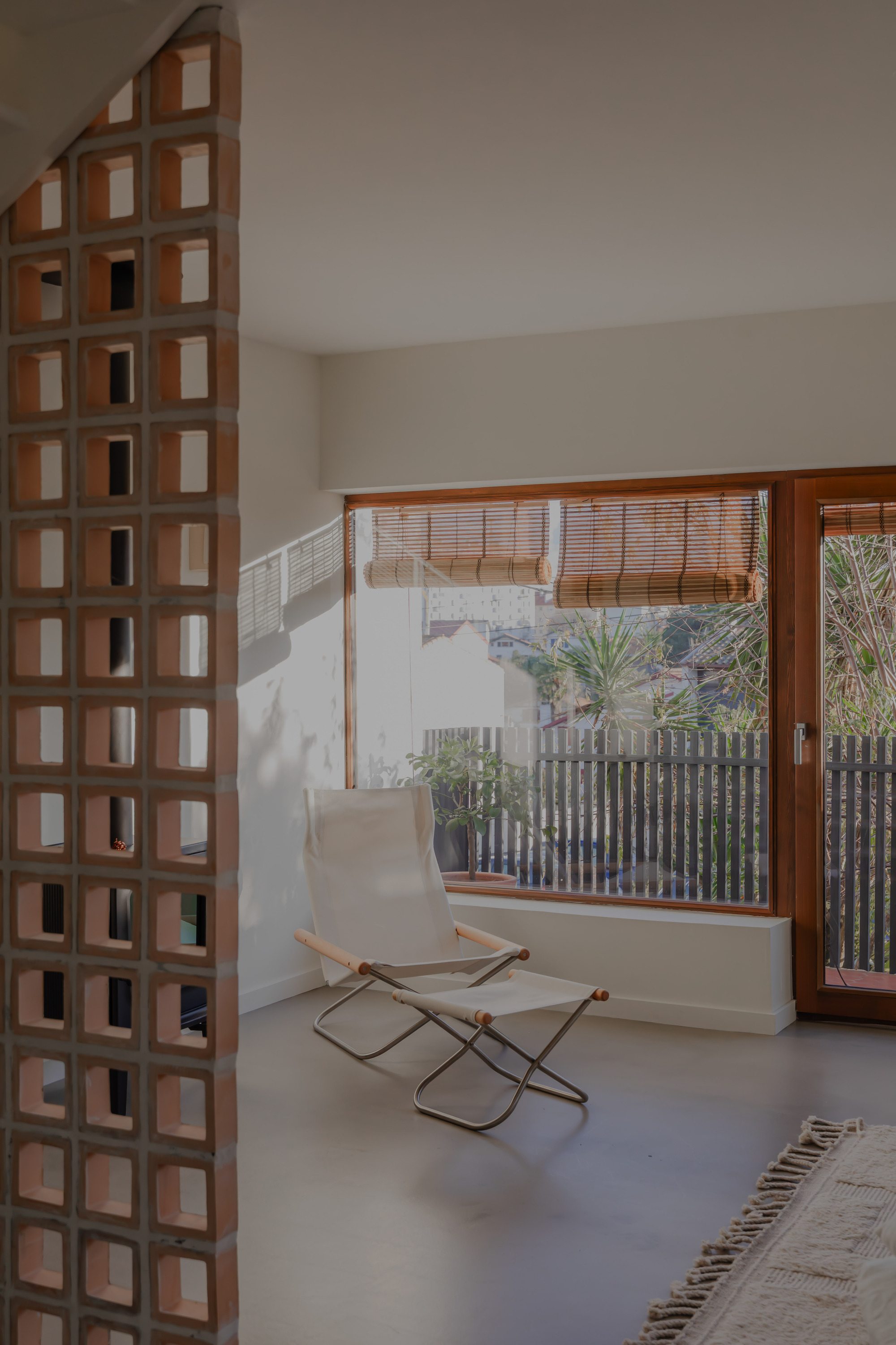 Timber gridded screen beside a window with bamboo blind overlooking a courtyard with vertical slat fencing
