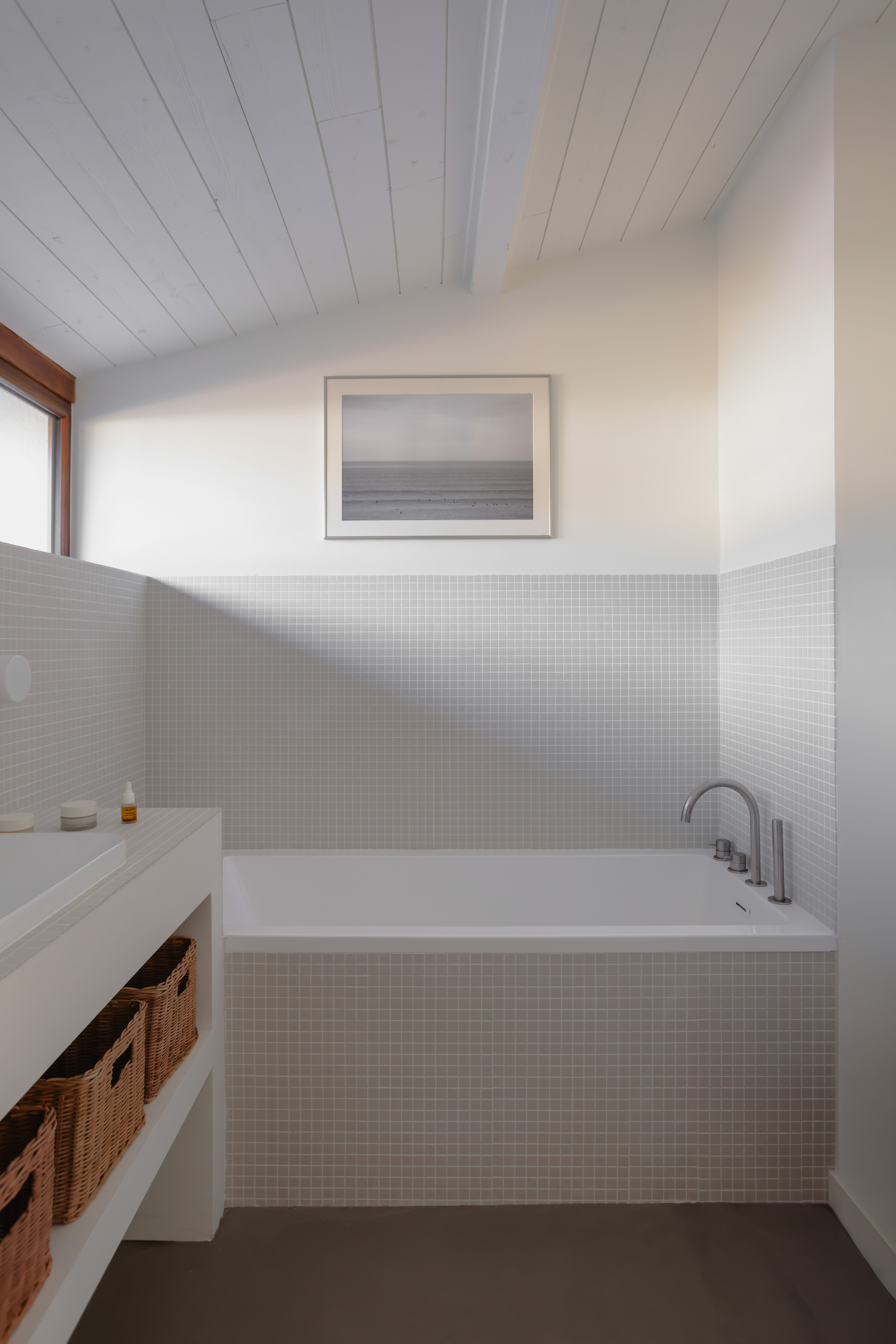 Bathroom with white mosaic tile tub surround, timber window trim and dark grey floor