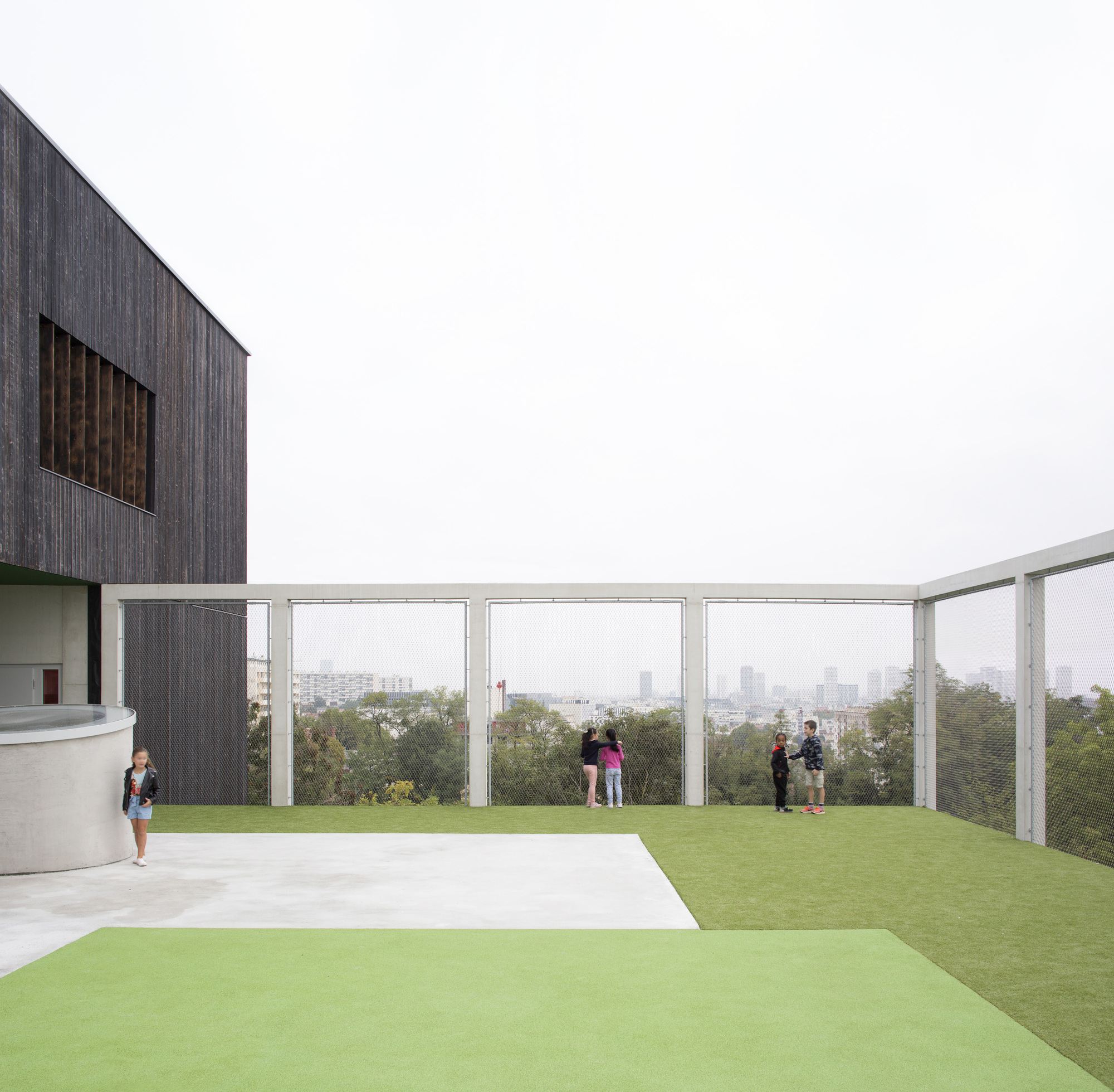 Rooftop terrace with white metal railing and visitors overlooking a distant cityscape in hazy light