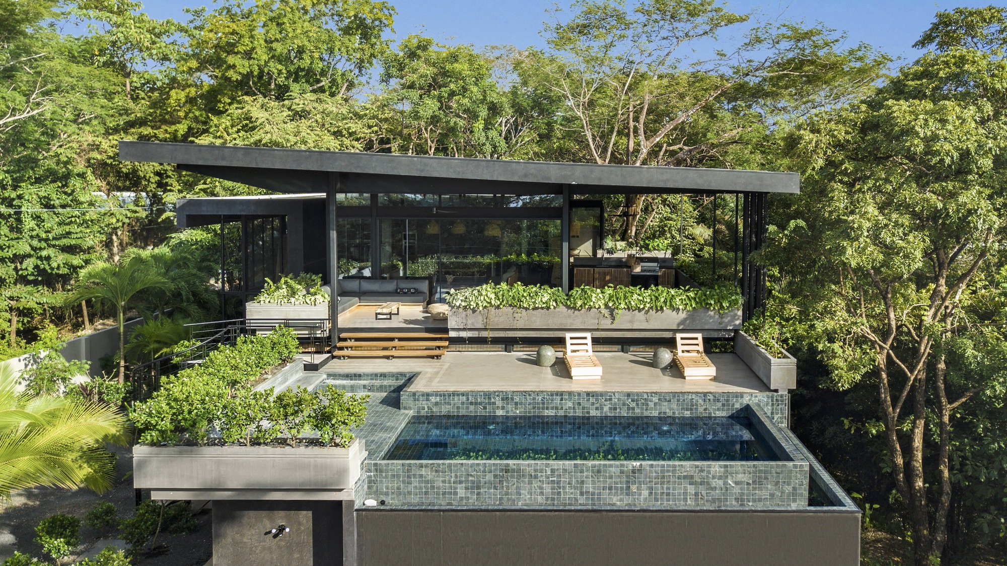 Tiered infinity pool with mosaic tile finish overlooking the forested canopy below