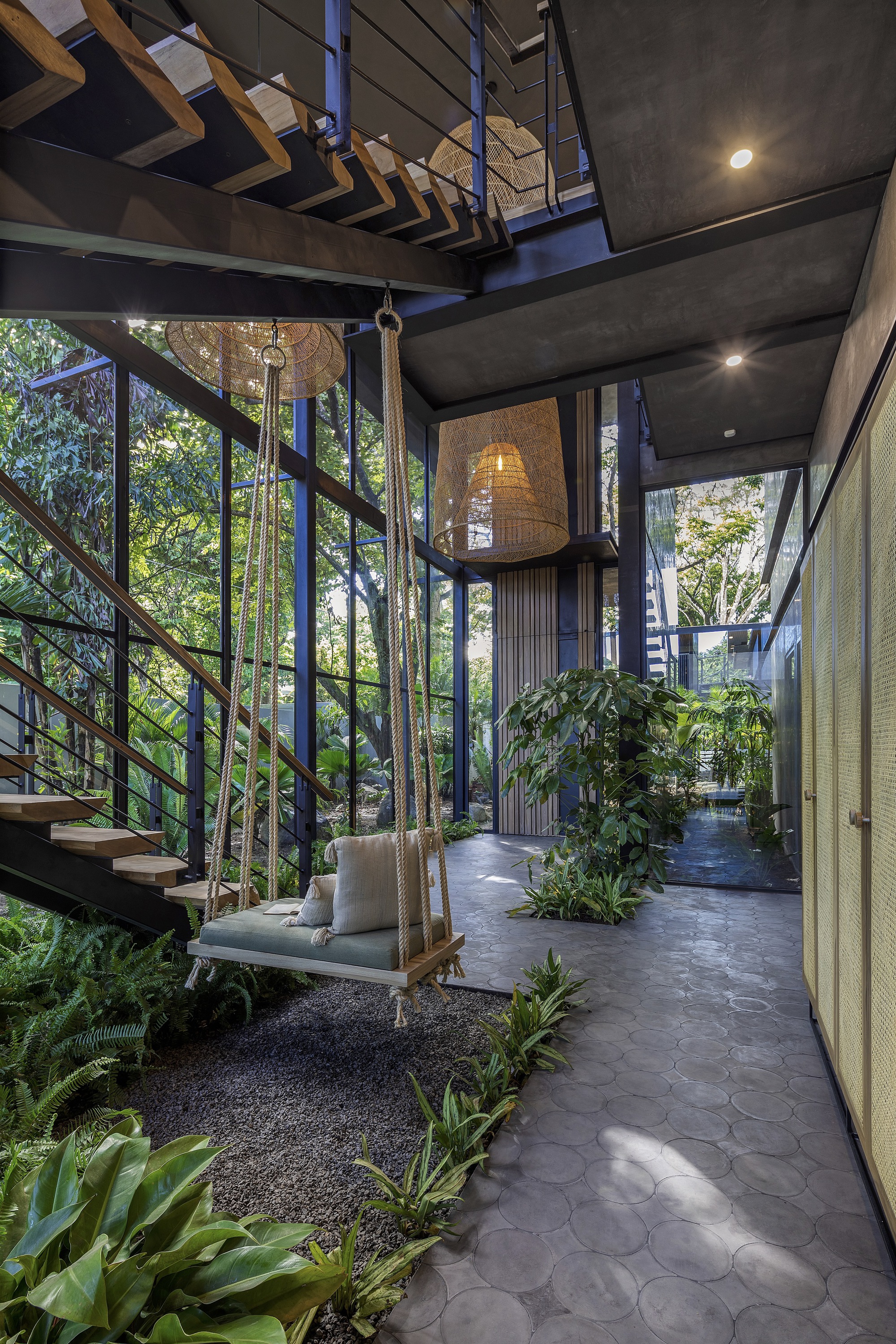 Interior courtyard with slate paving, hanging swing seat, and floor-to-ceiling glazing filtering daylight