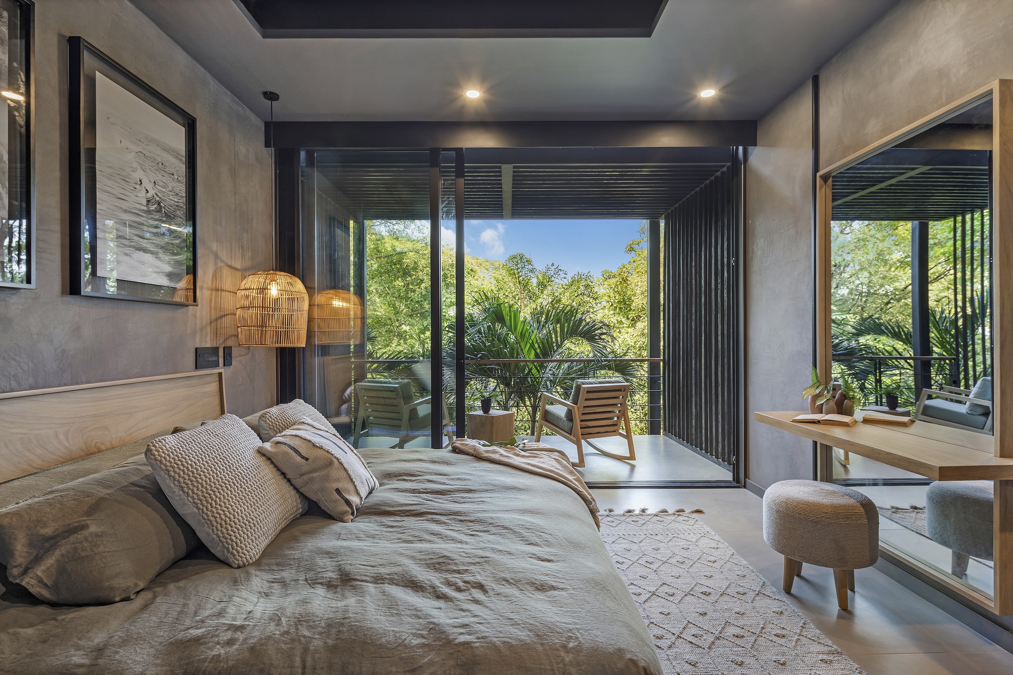 Bedroom with glass doors opening to a private balcony framed by foliage