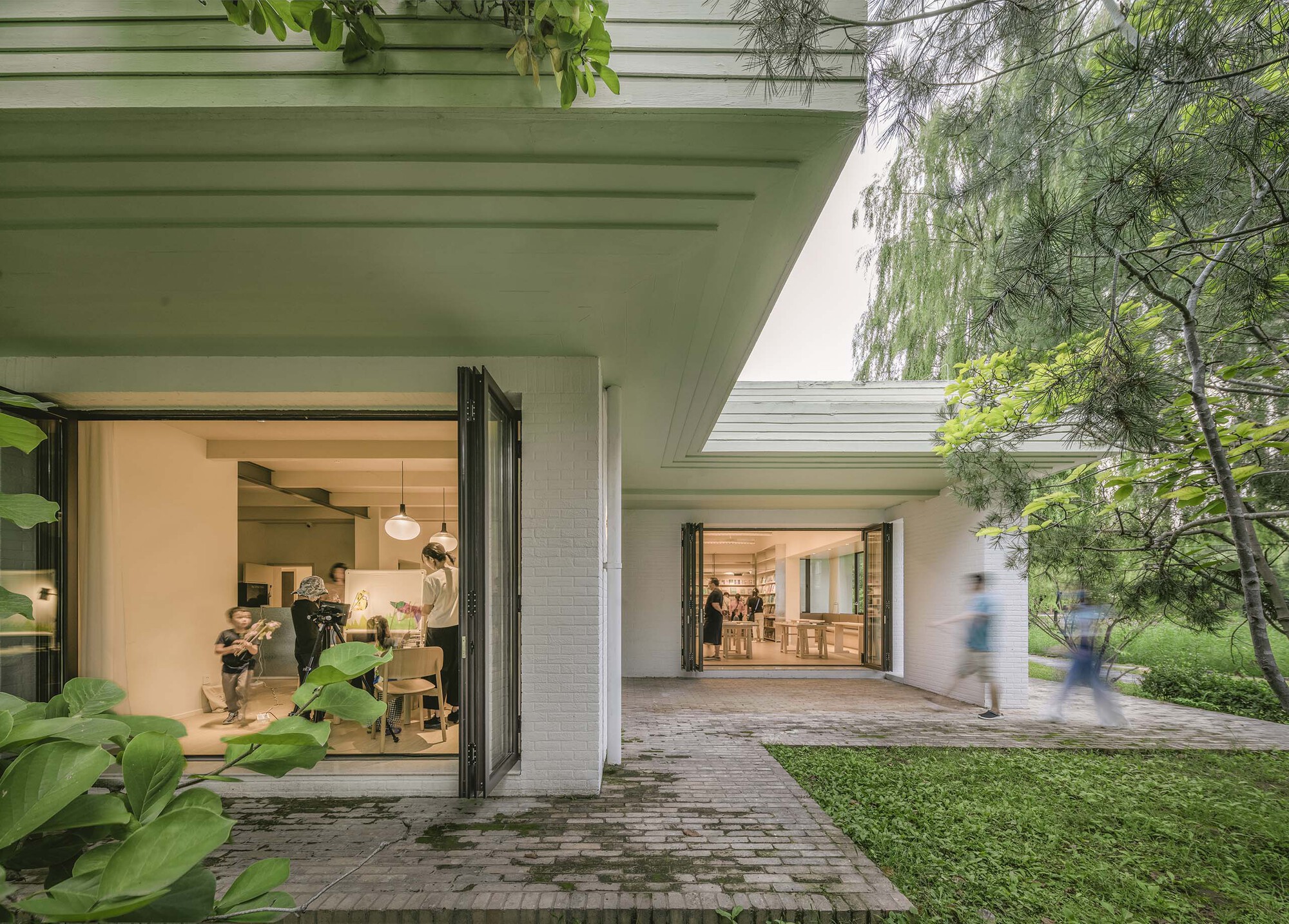 Covered walkway with exposed concrete ceiling beams and open folding doors leading to interior rooms
