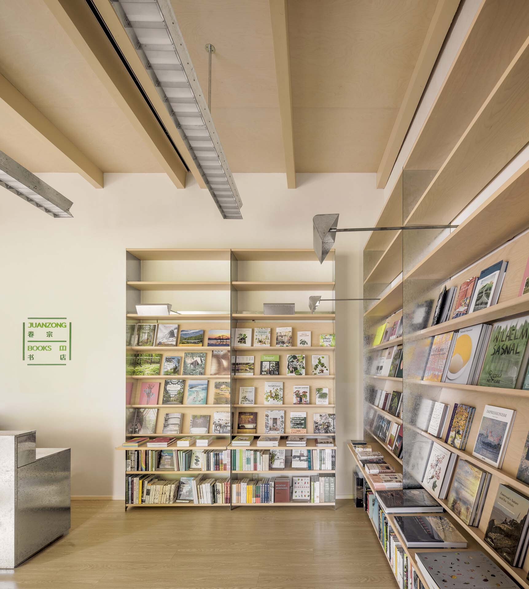 Interior library space with floor-to-ceiling shelving displaying books and exposed wooden ceiling beams