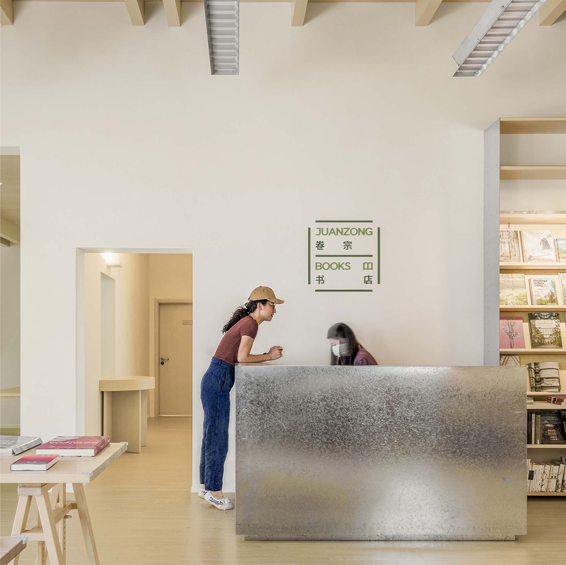 Textured concrete reception desk with a visitor in a straw hat standing at the counter