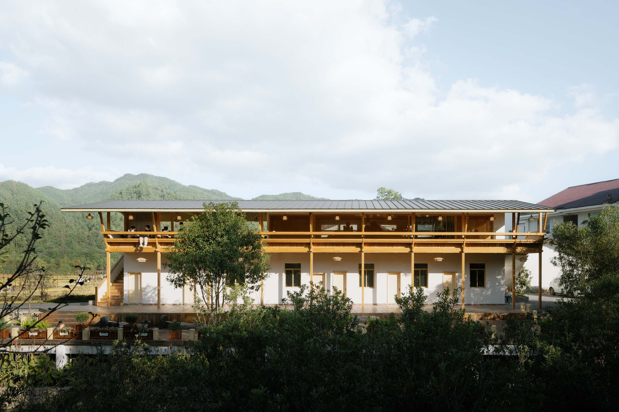 Three-story facade with exposed timber frame and deep overhanging eaves set against forested mountains