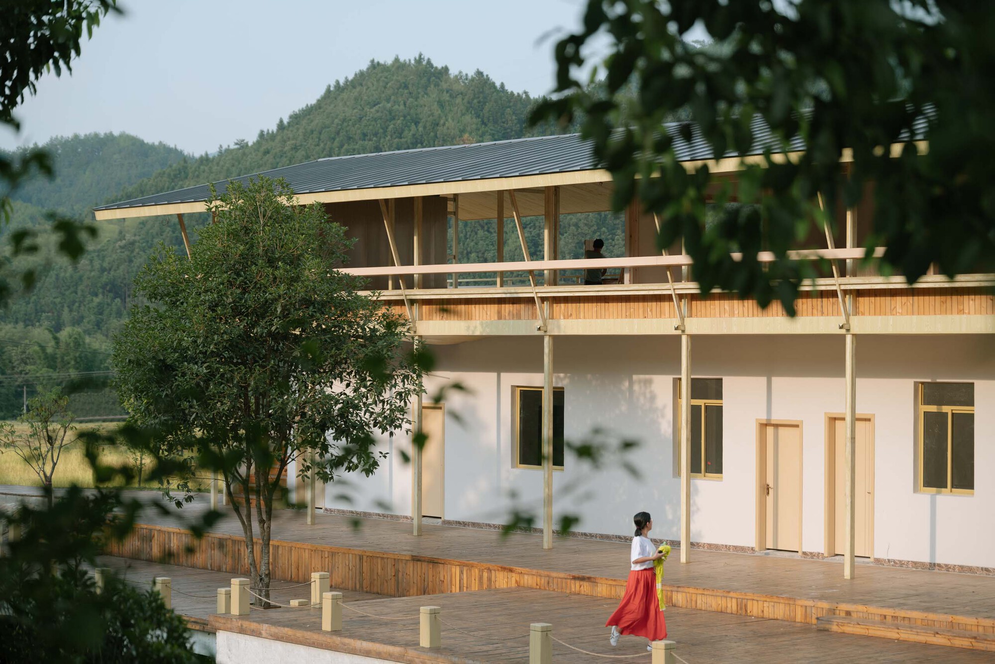 Corner detail showing timber columns and cross-bracing beneath the cantilevered upper floor at dusk
