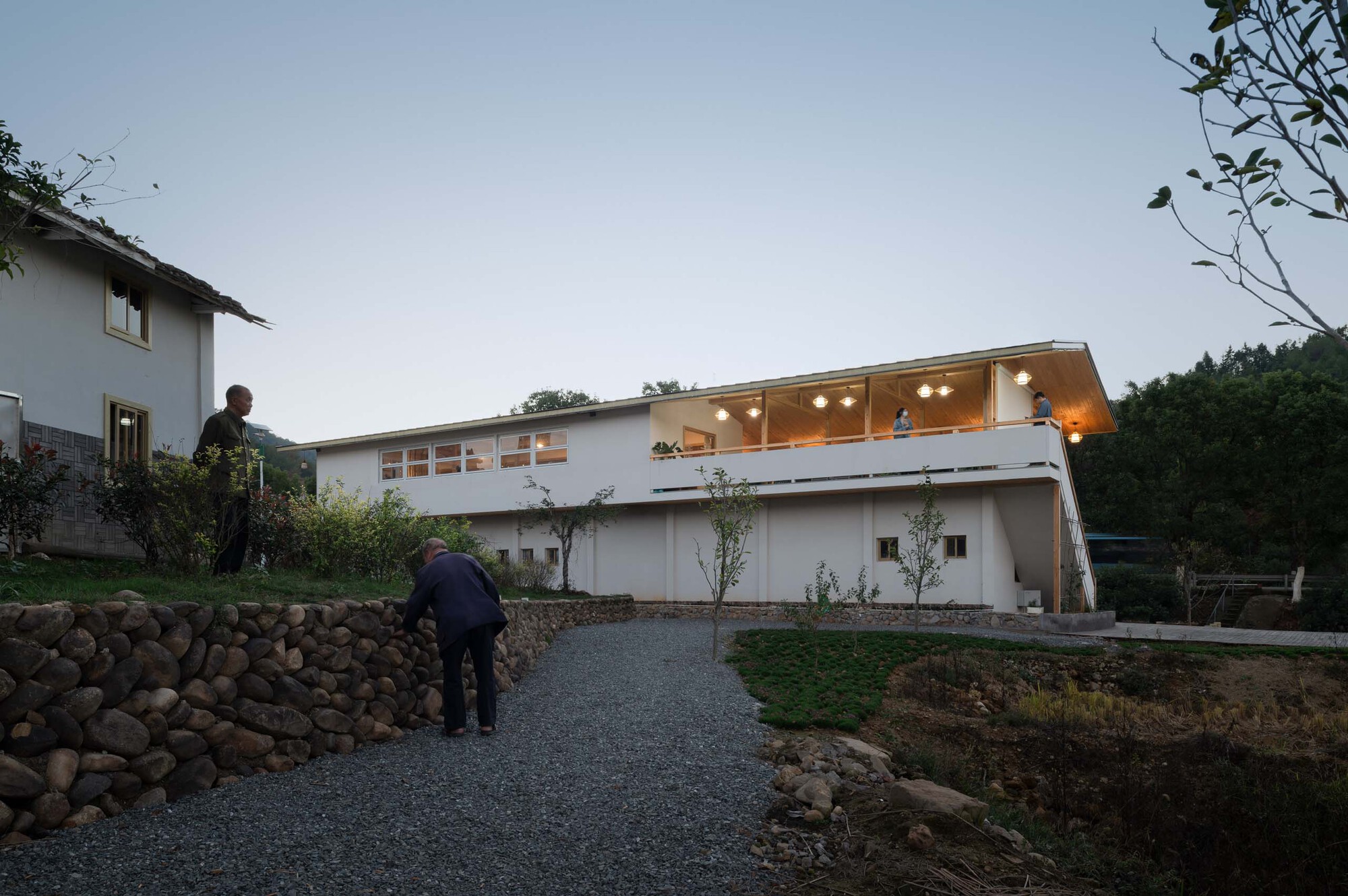 Illuminated upper-level living space with exposed timber structure and figures visible inside at dusk