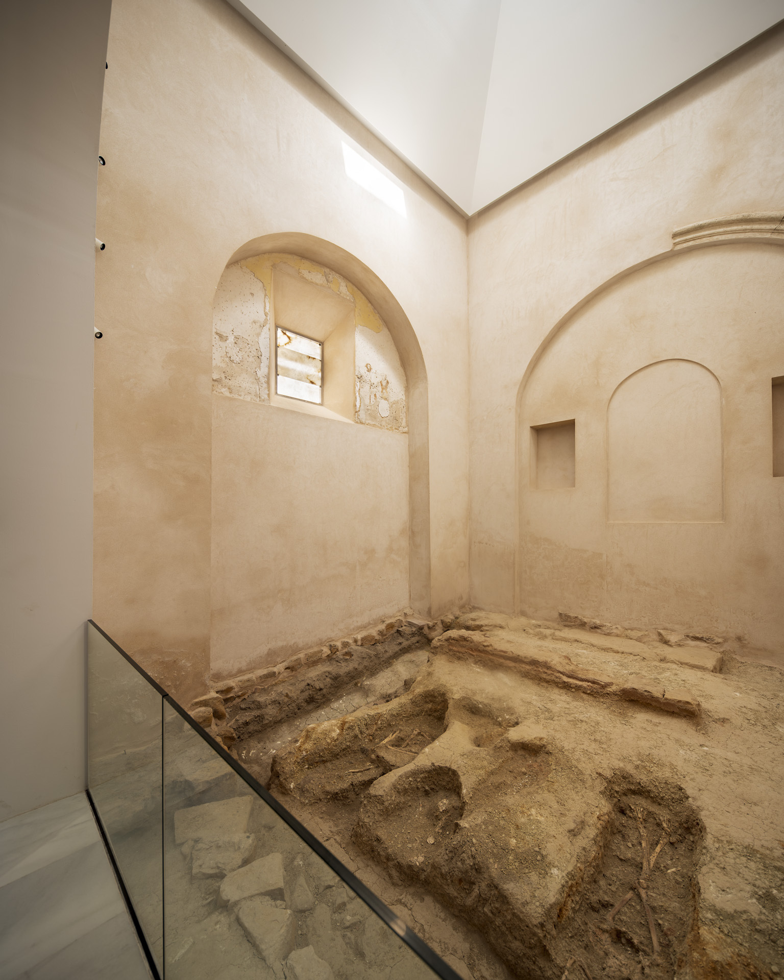 Interior view of restored arched chamber with exposed archaeological remains protected by a glass barrier