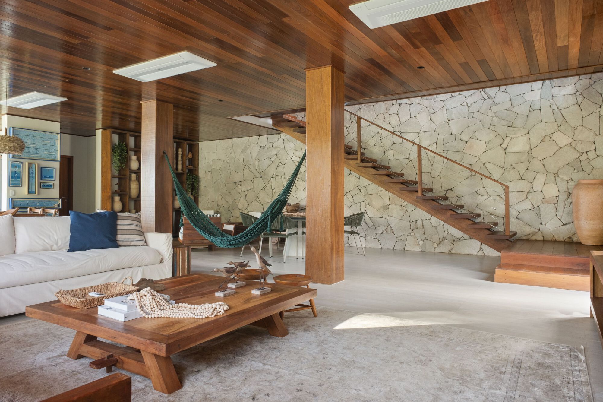 Floating timber staircase with steel railing ascending against a cream stone mosaic wall