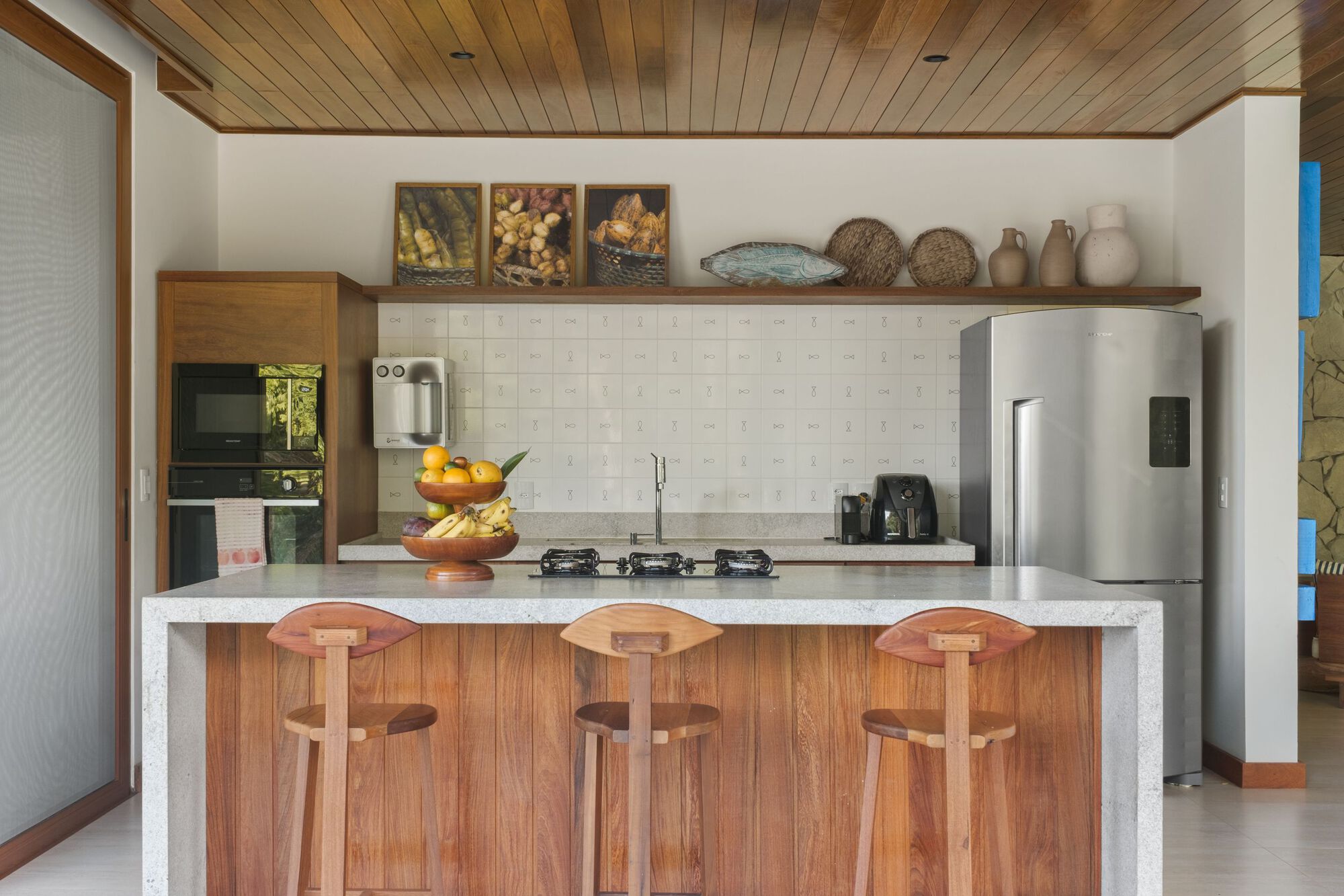 Kitchen counter with white tile backsplash and three timber bar stools beneath a wood plank ceiling