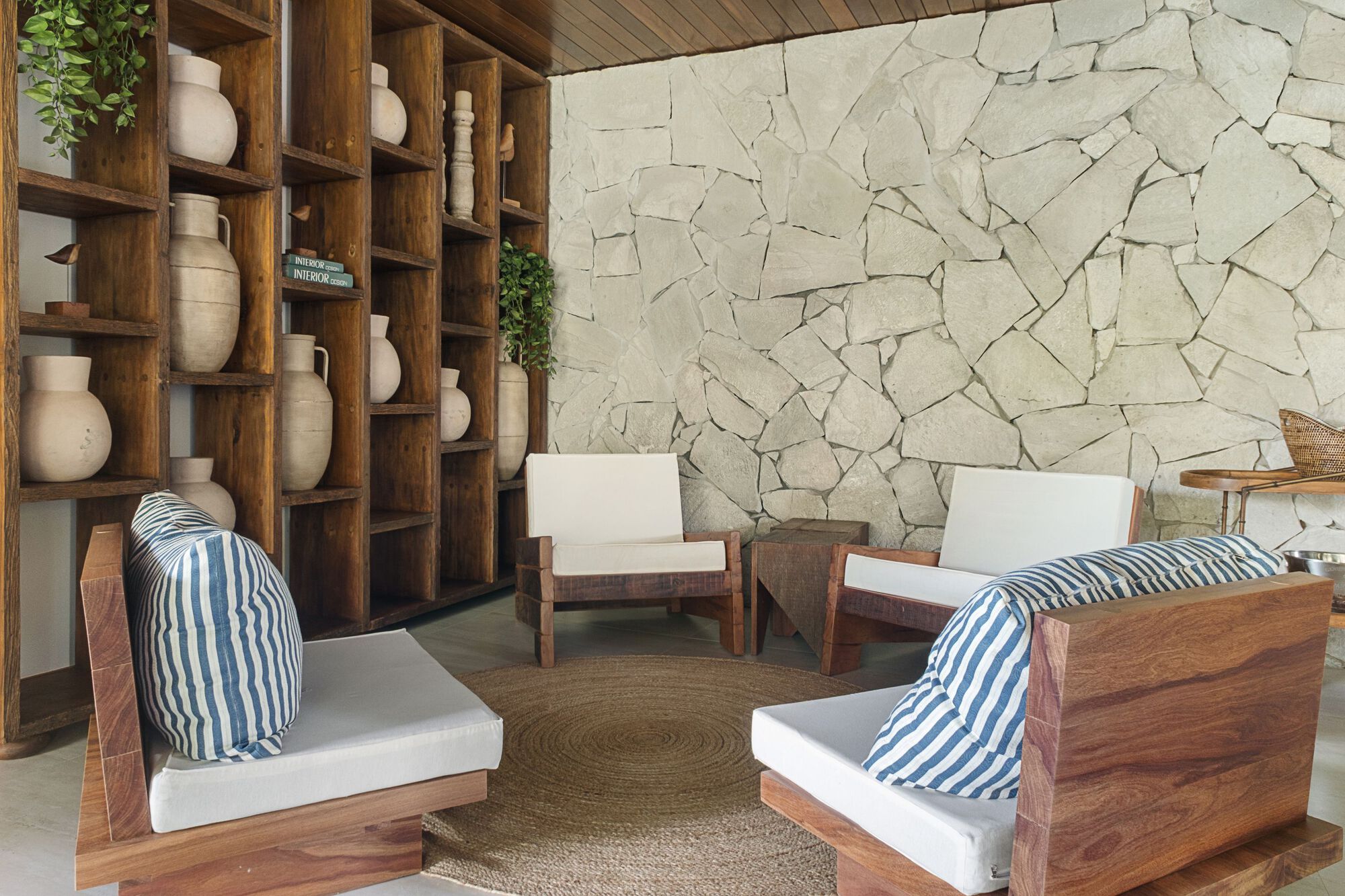 Seating nook with timber lounge chairs, striped cushions and a stone mosaic accent wall