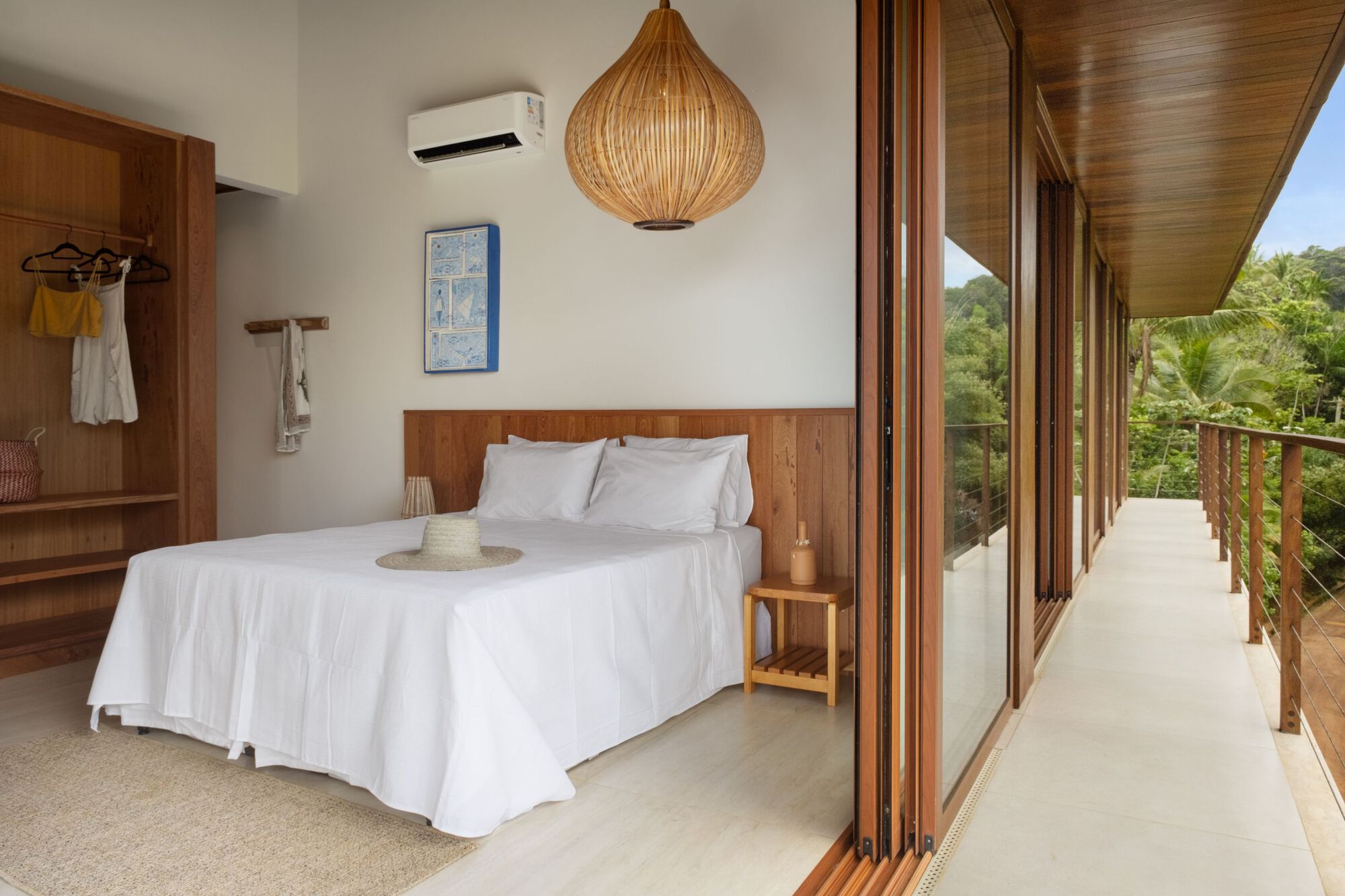 Bedroom opening to an exterior timber balcony with views of palm trees