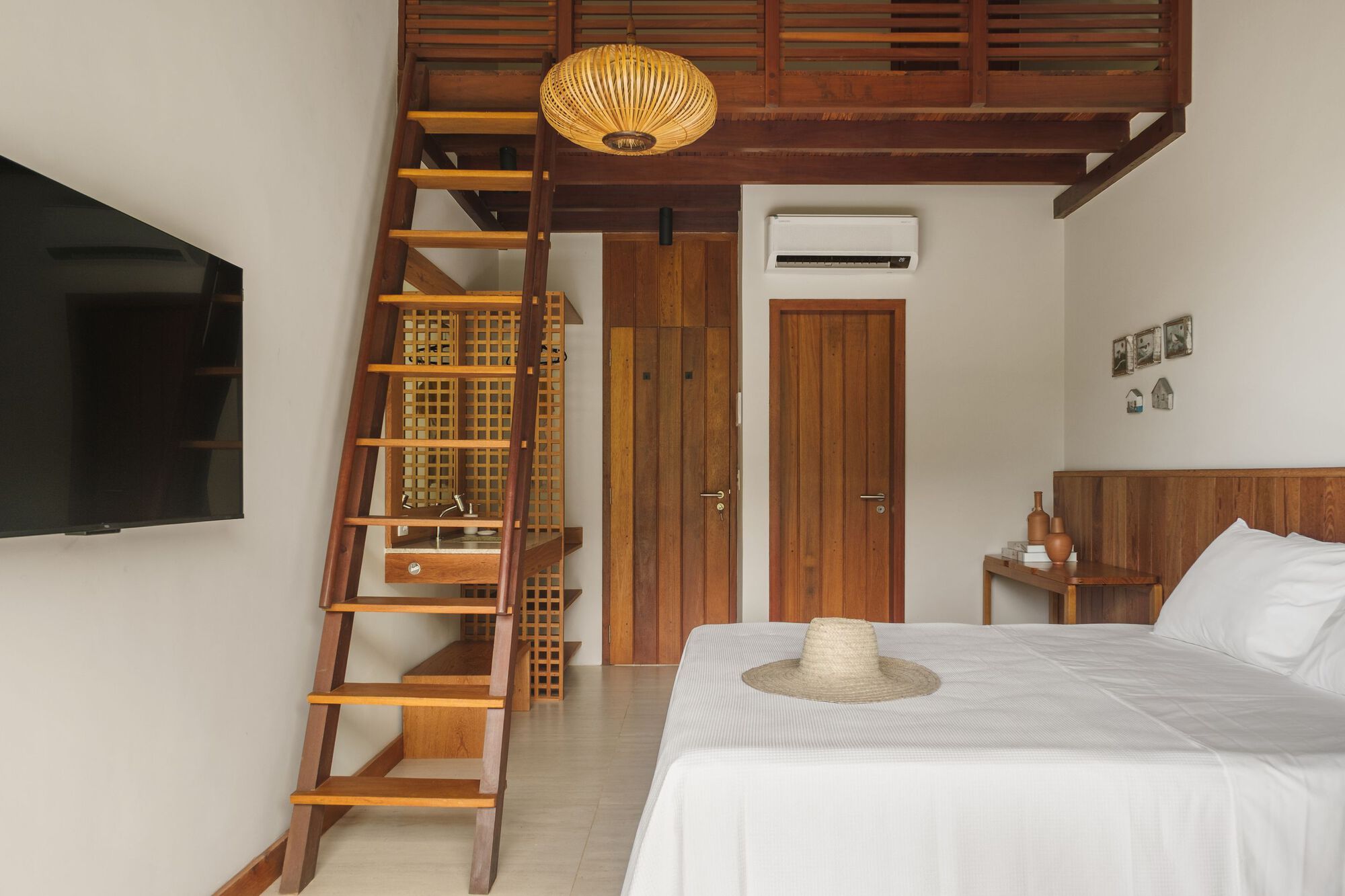 Bedroom with timber ladder accessing a mezzanine storage loft above