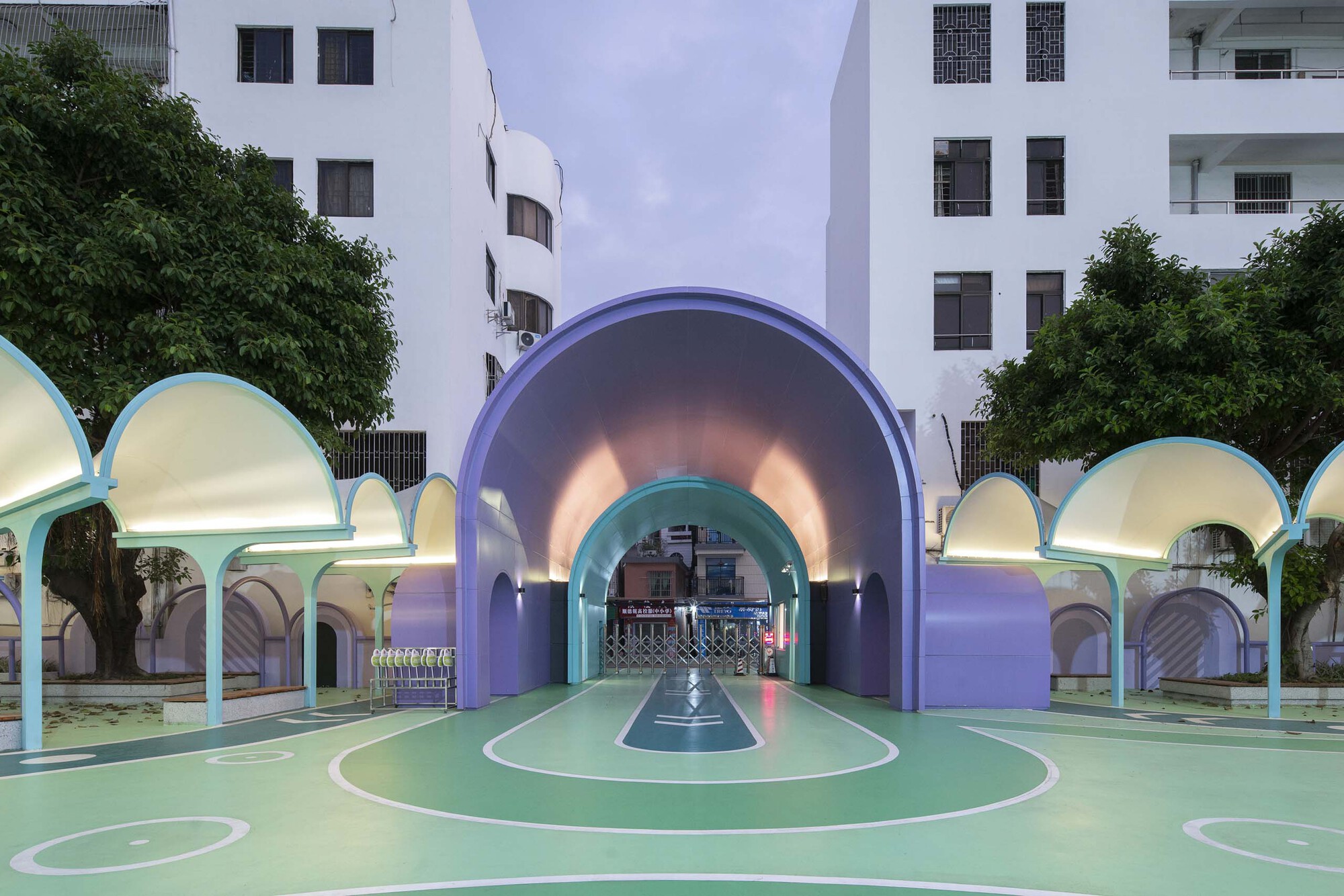 Illuminated purple arched portal framing the entry gate at dusk between rows of white dome canopies