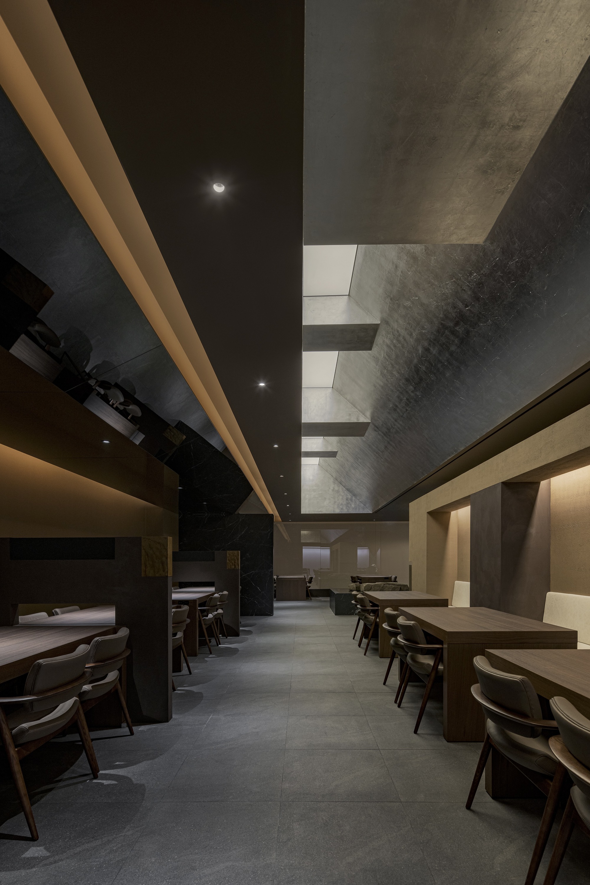 Dining corridor showing rows of tables beneath a suspended slot skylight and black ceiling planes