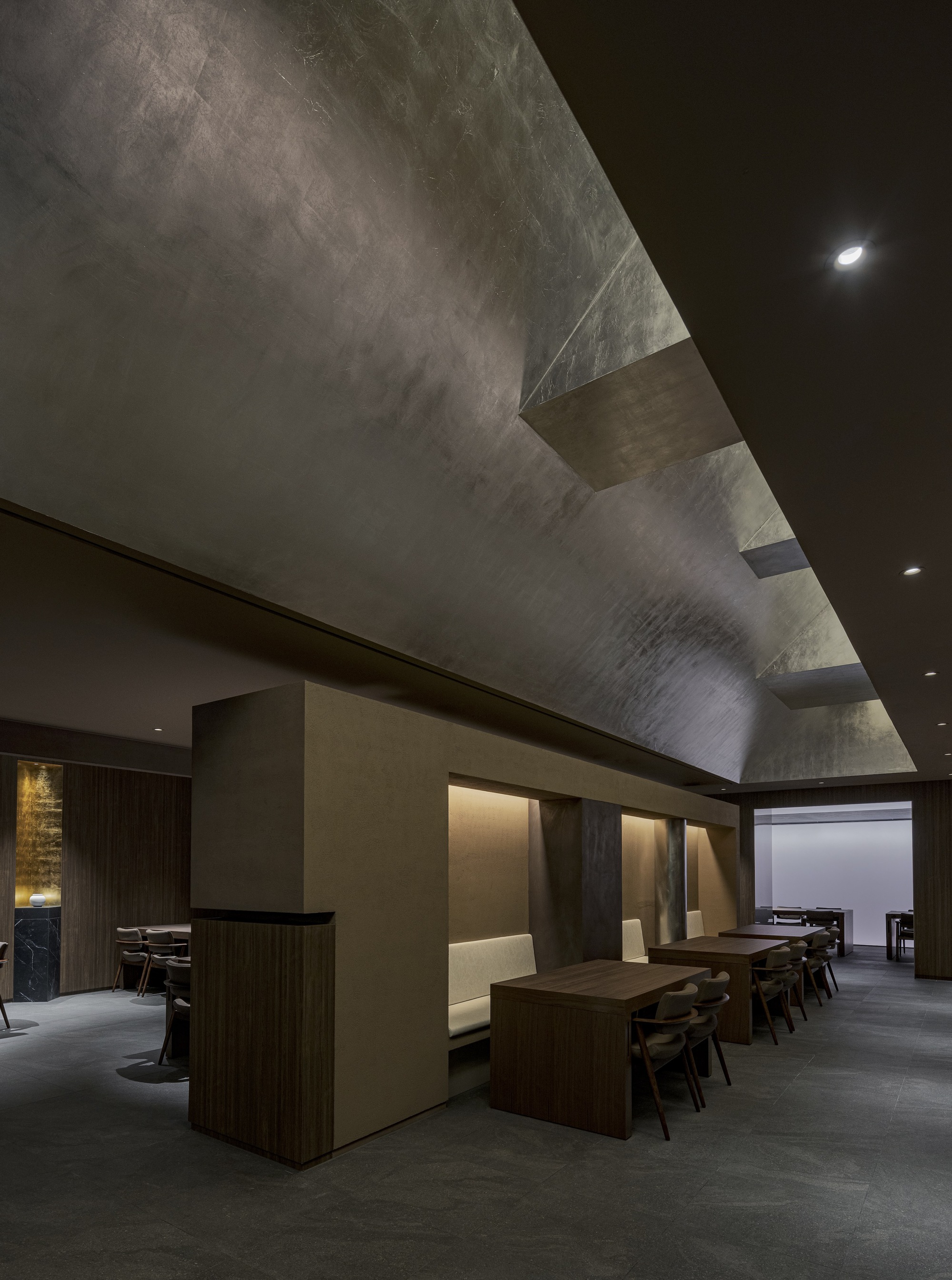 View toward dining booths with angled skylight casting natural light across the textured ceiling surface