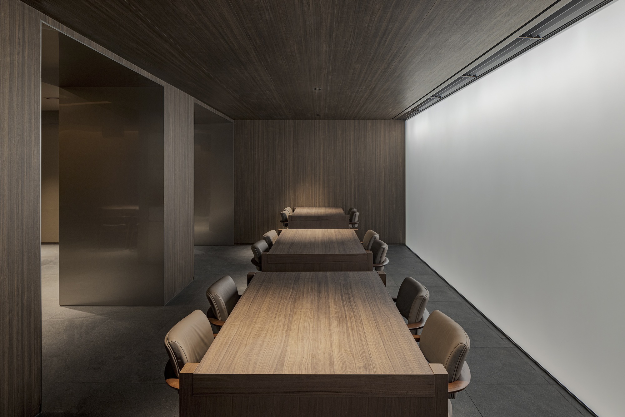 Semi-private dining space with timber tables and translucent wall panel illuminated from behind