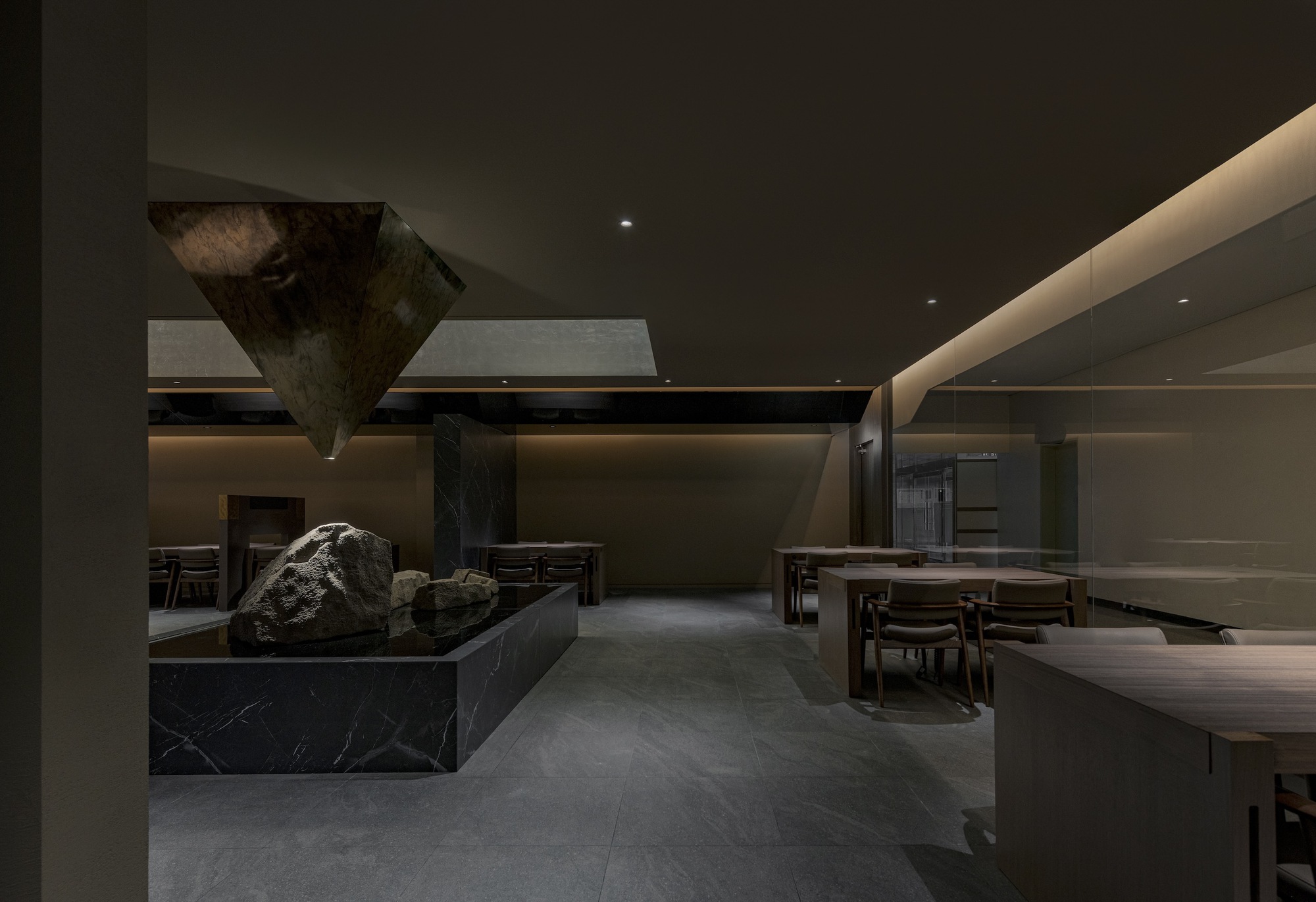 View across the dining area showing the stone installation and polished ceiling planes overhead