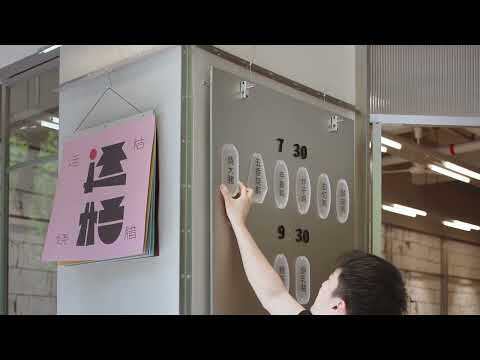 Hand adjusting circular signage elements on glass storefront beneath a pink poster