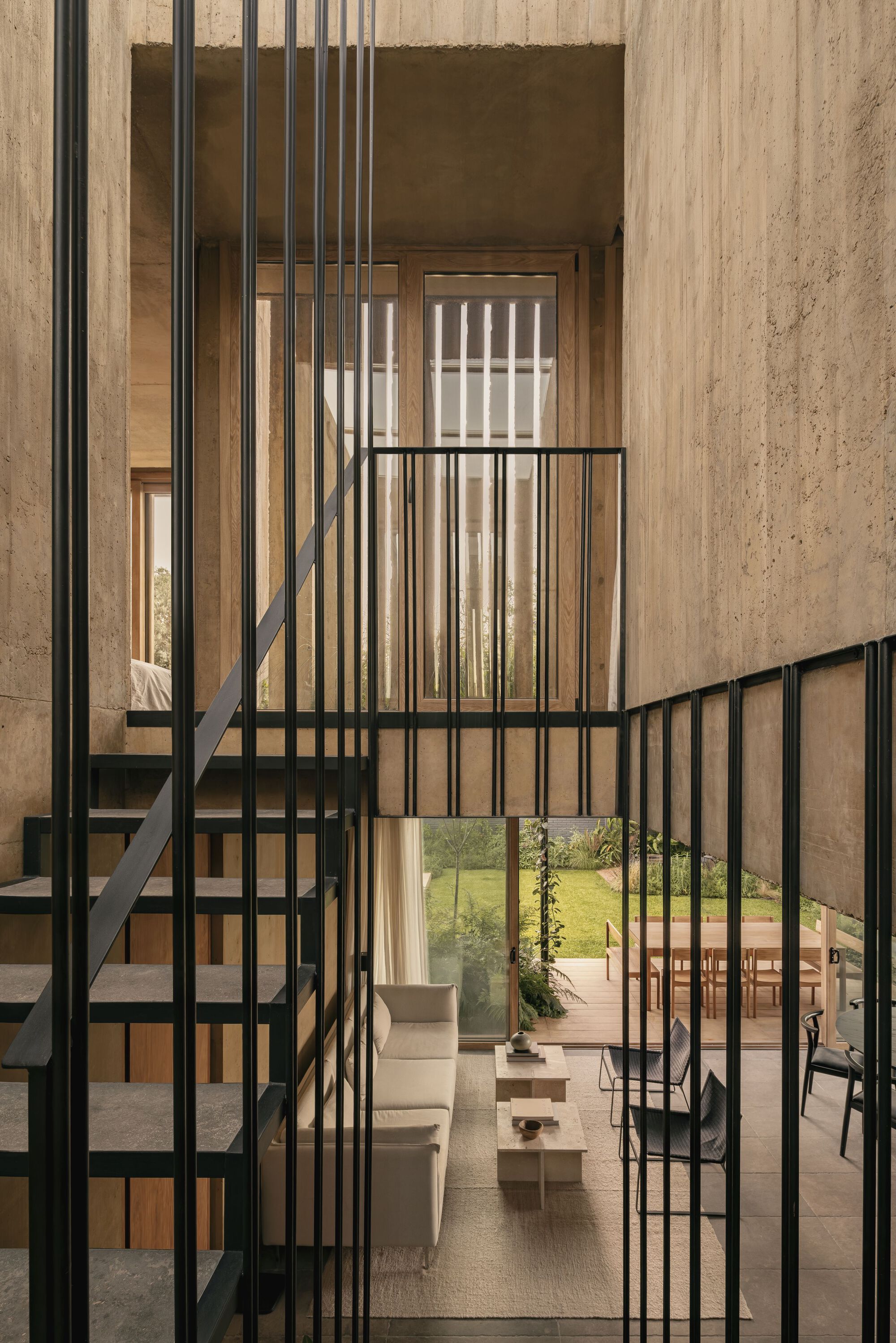 Steel staircase framed by vertical metal rods connecting multiple levels through the void