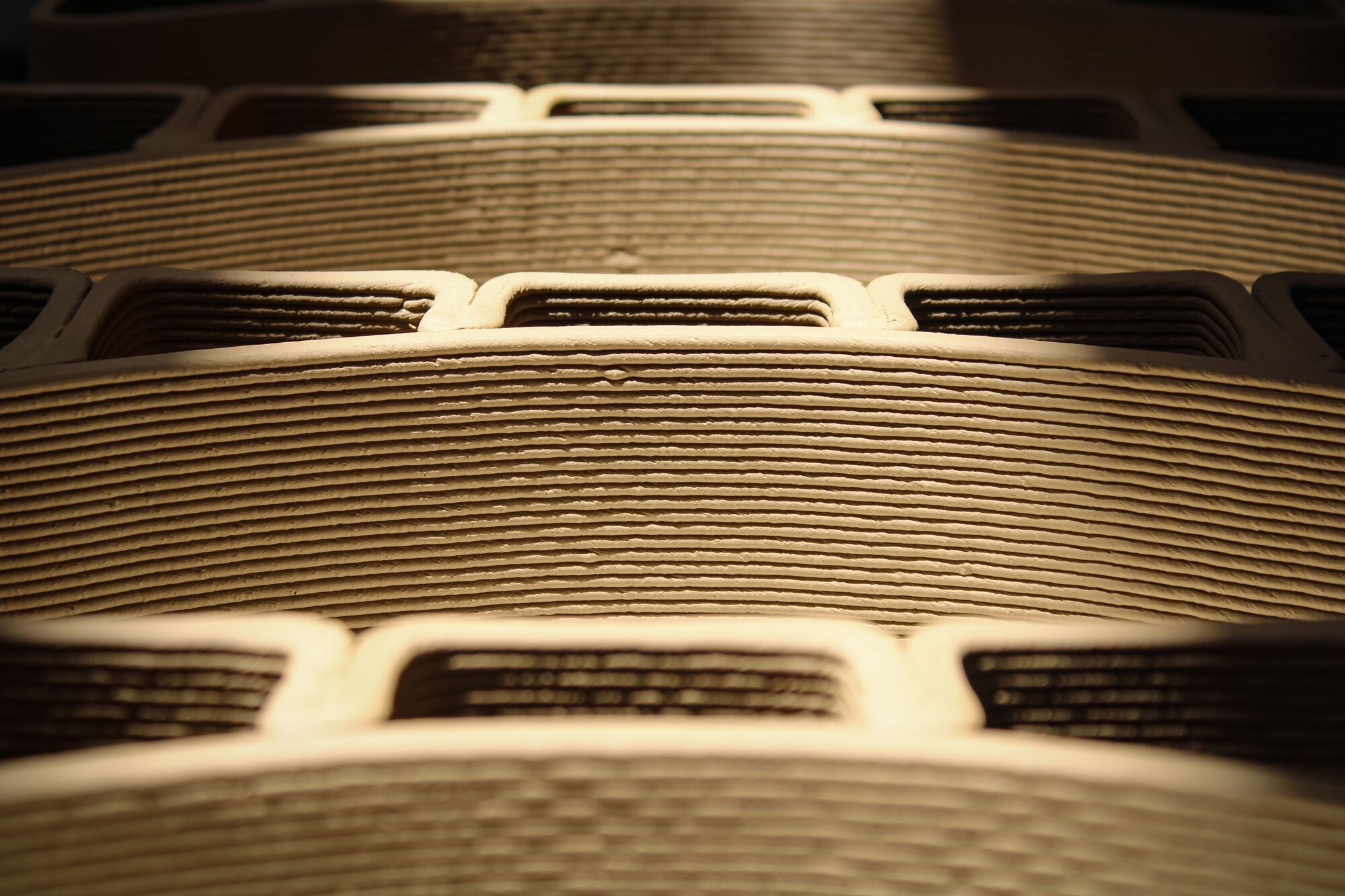 Detail view of layered cardboard or laminated material showing horizontal striations and rectangular cutouts in dramatic lighting
