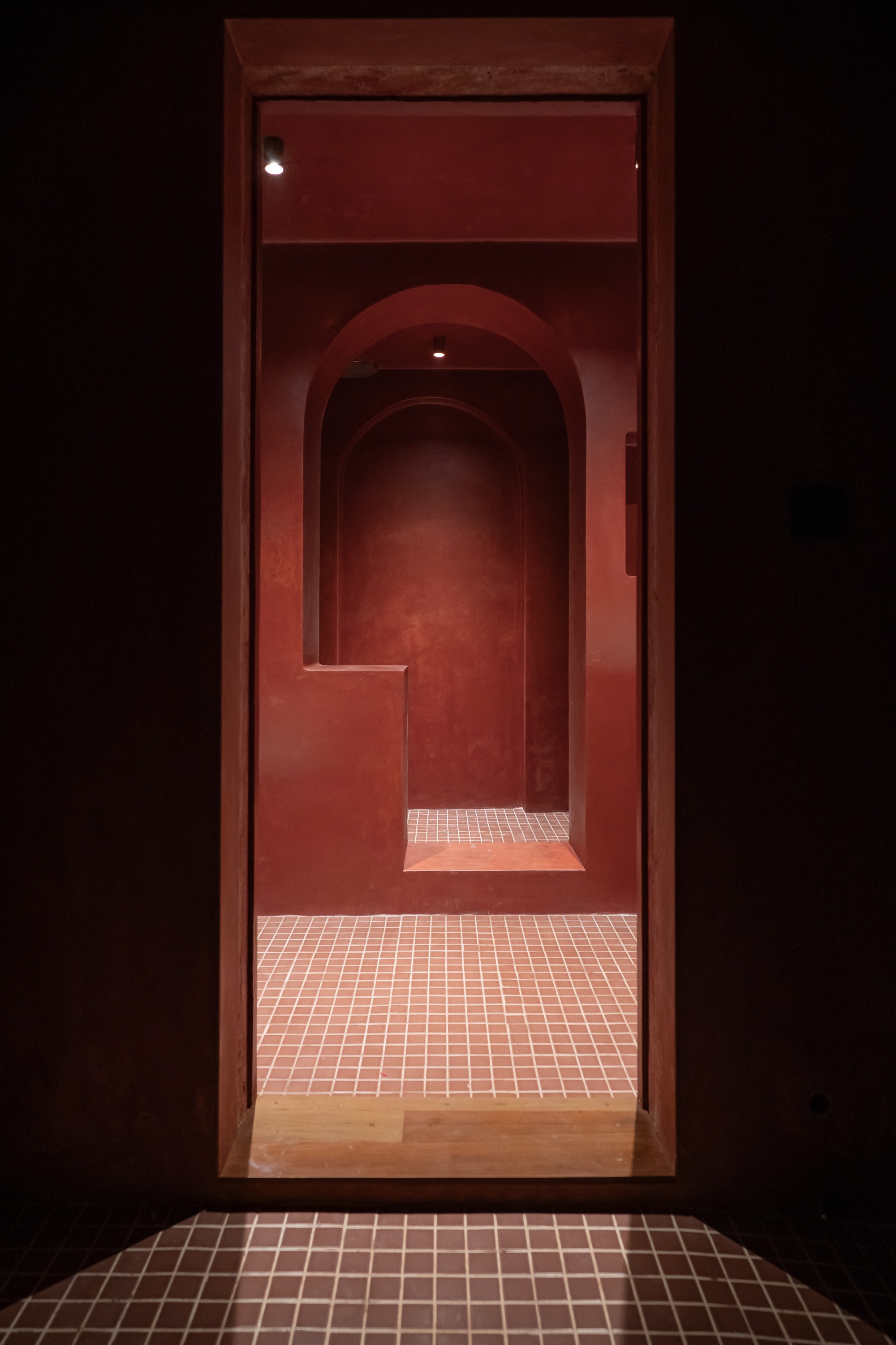 Sequence of arched doorways receding into darkness with tiled threshold and red plastered walls