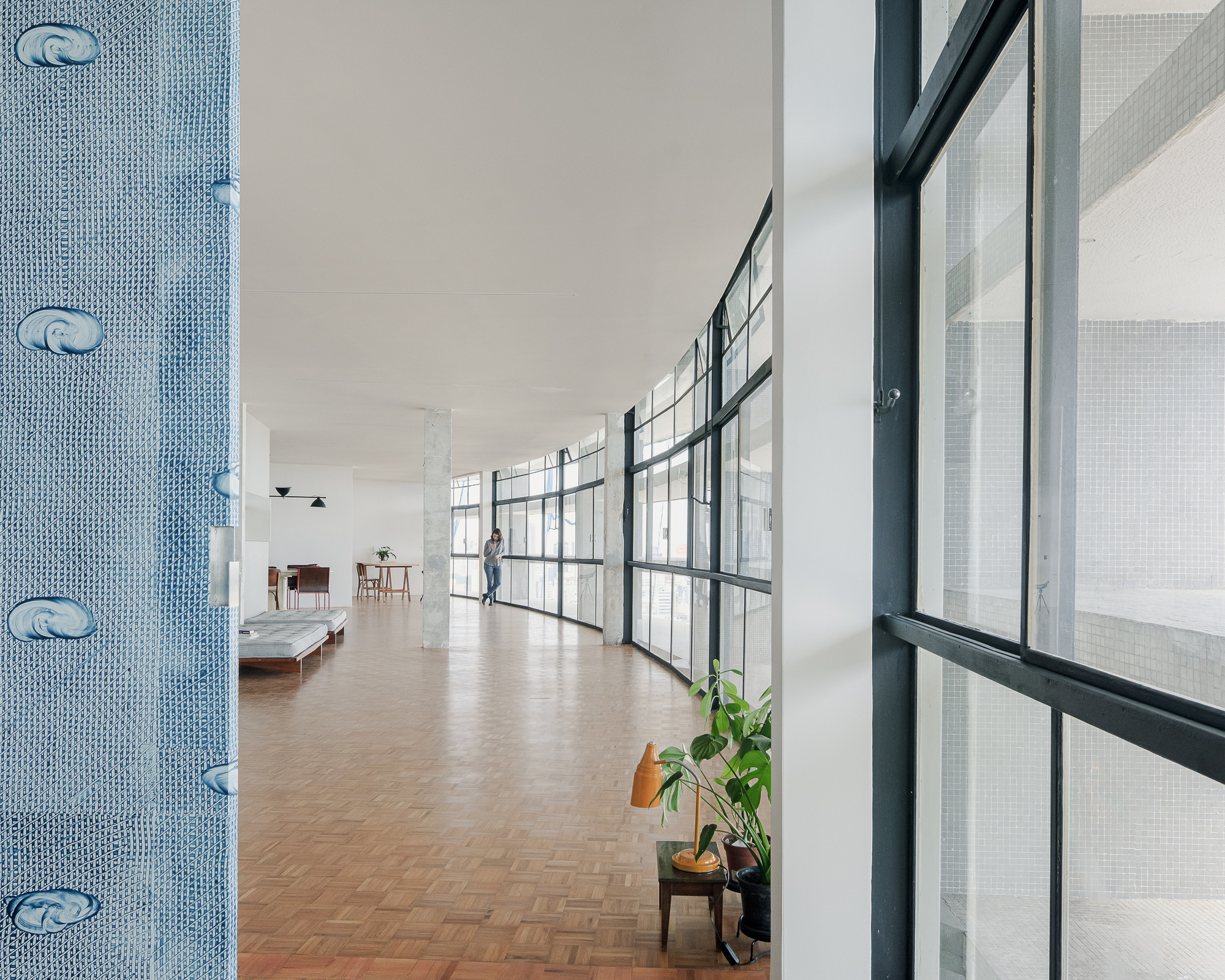 Long corridor with herringbone parquet flooring and grid-patterned glazing along one side