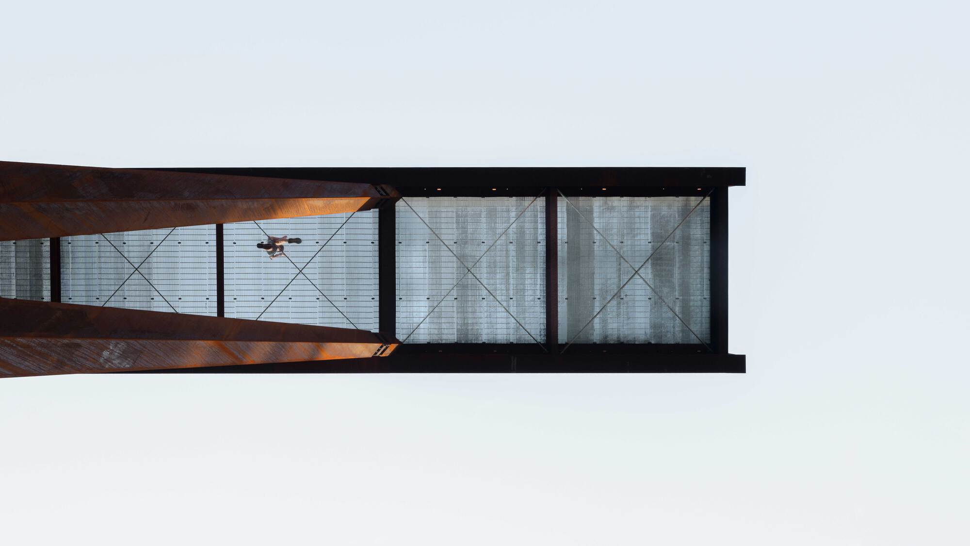 Bottom view of the pedestrian bridge deck showing translucent panels with diagonal cross bracing and steel beams